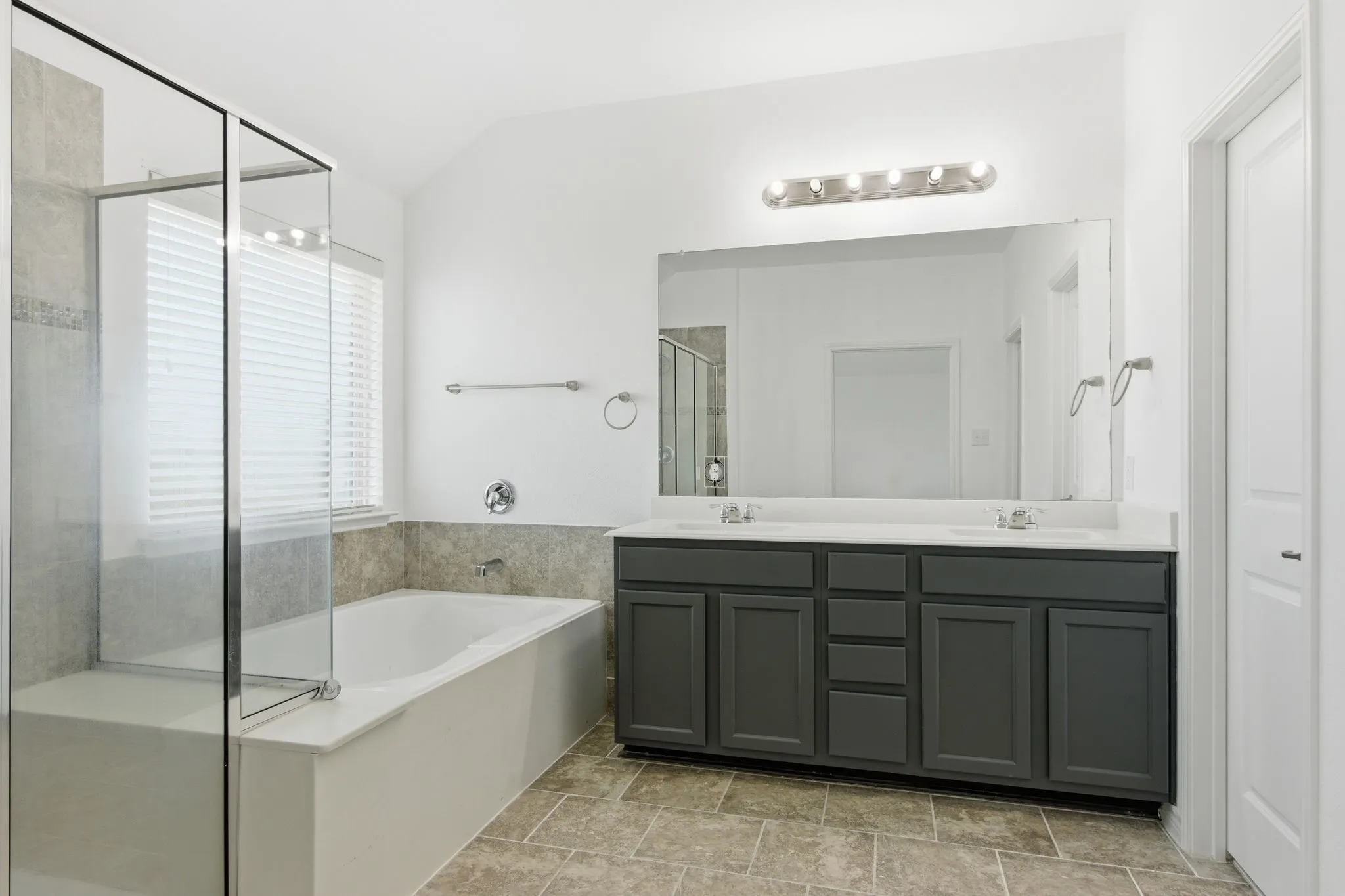 Dual vanity with dark cabinetry, white countertops, and chrome fixtures