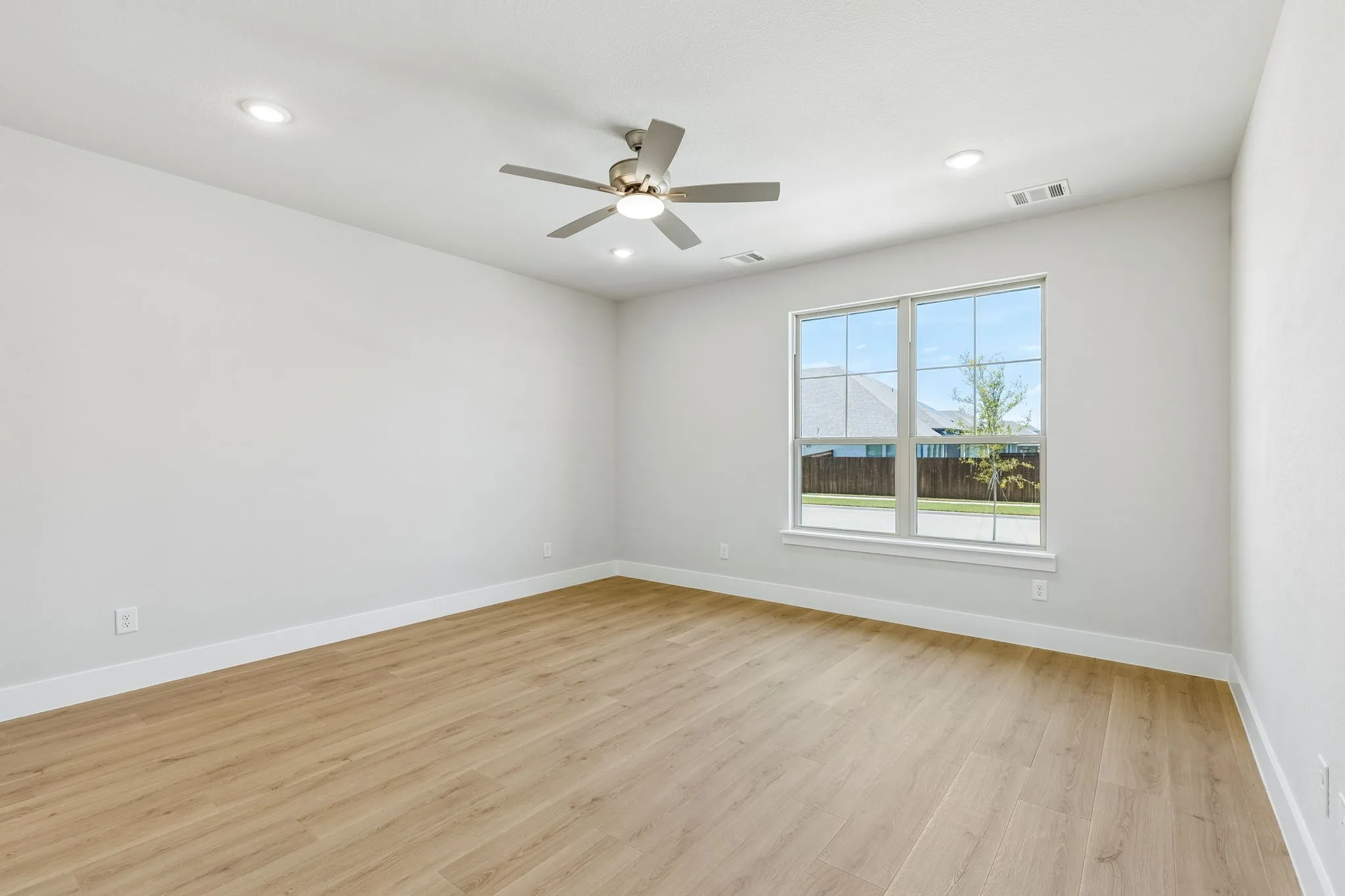 Recessed ceiling lighting, wood-finish flooring, ceiling fan with integrated lighting, multiple windows, and crisp white walls