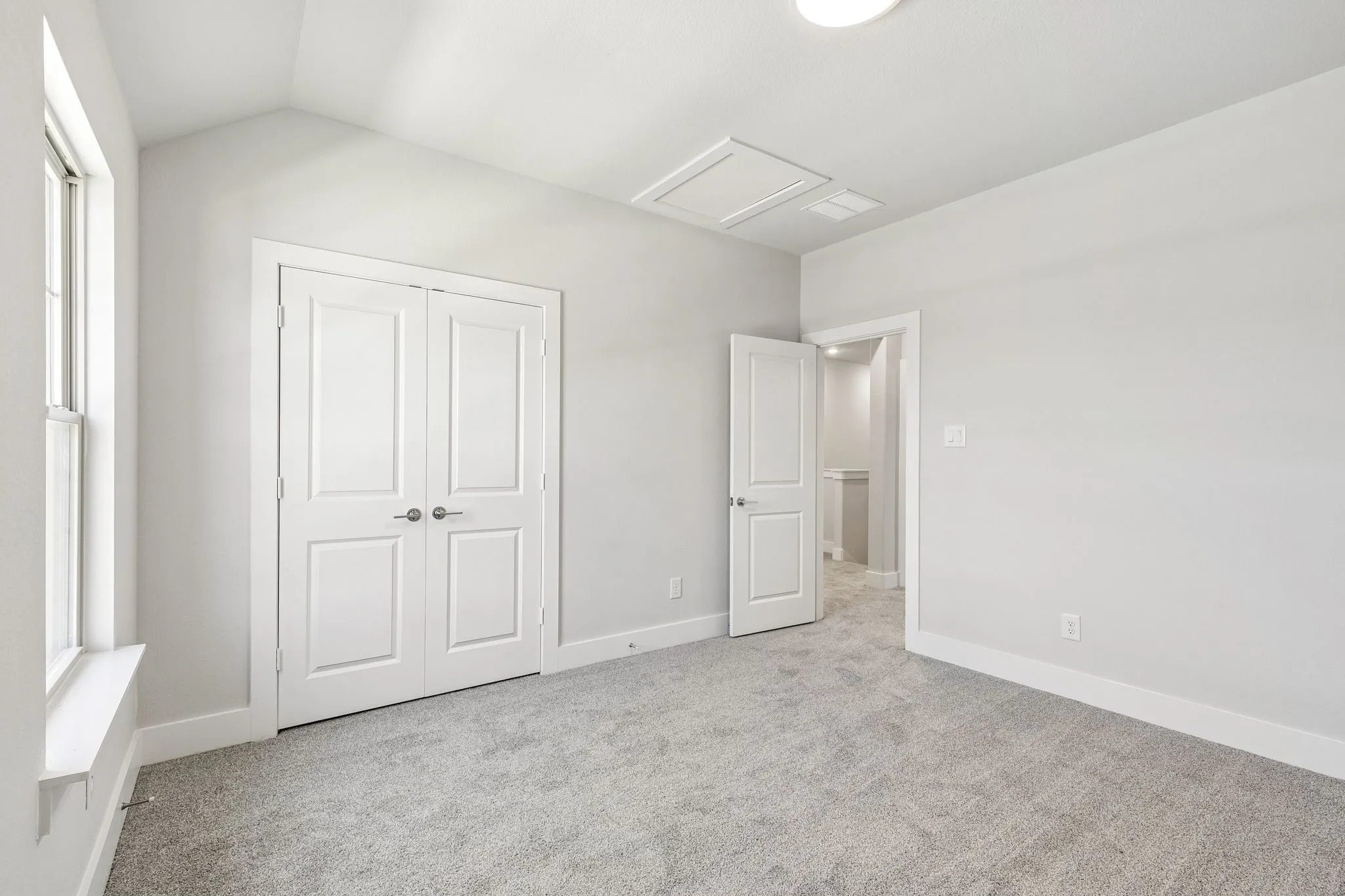 Vaulted ceiling, double-panel interior doors, light-colored carpeting, single-hung window, and a flush-mount ceiling light