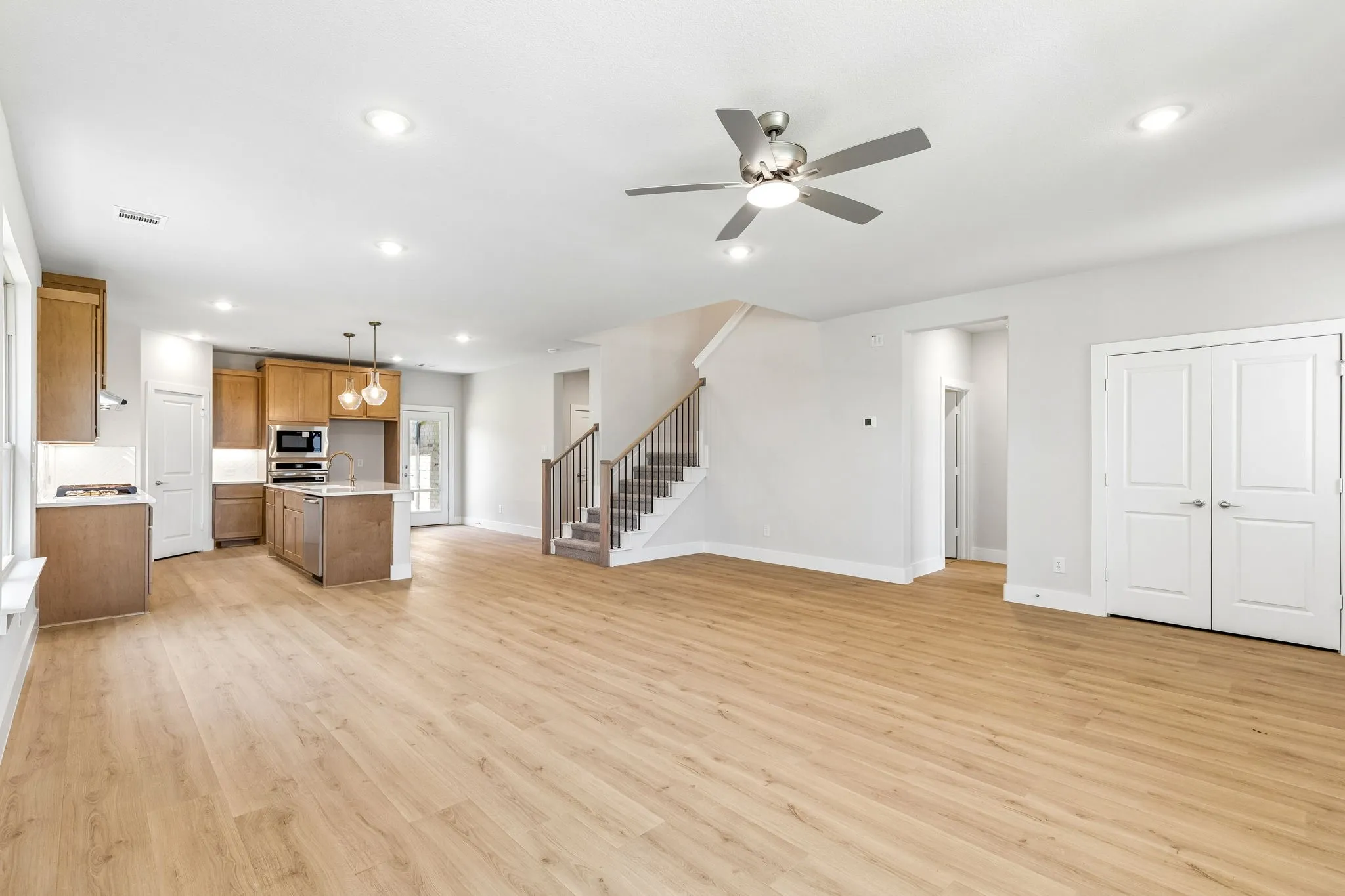 Open-concept living area featuring wood-finish flooring, recessed lighting, and a ceiling fan