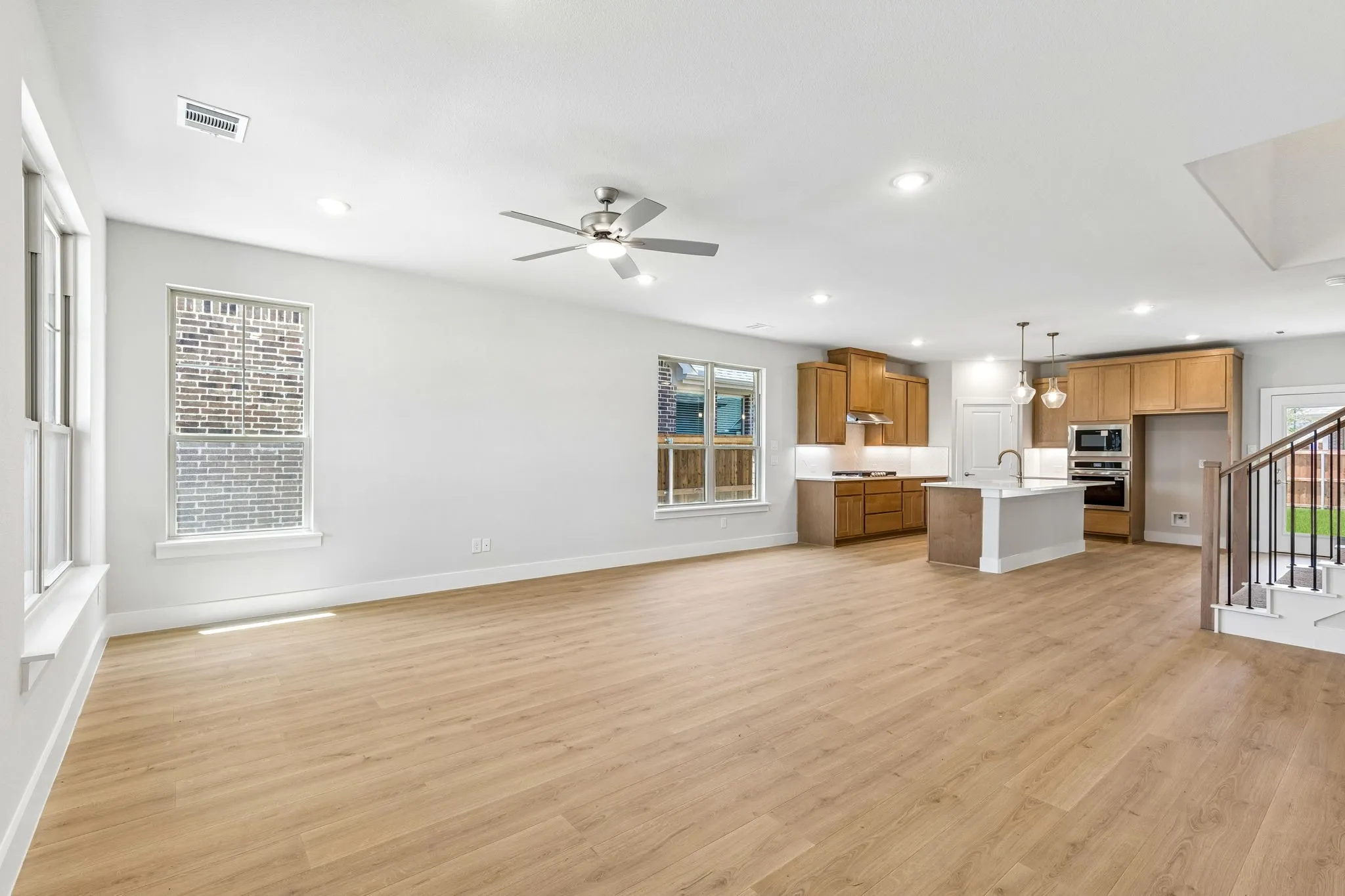 Expansive open-concept living area with wood-finish flooring, recessed lighting, and a ceiling fan