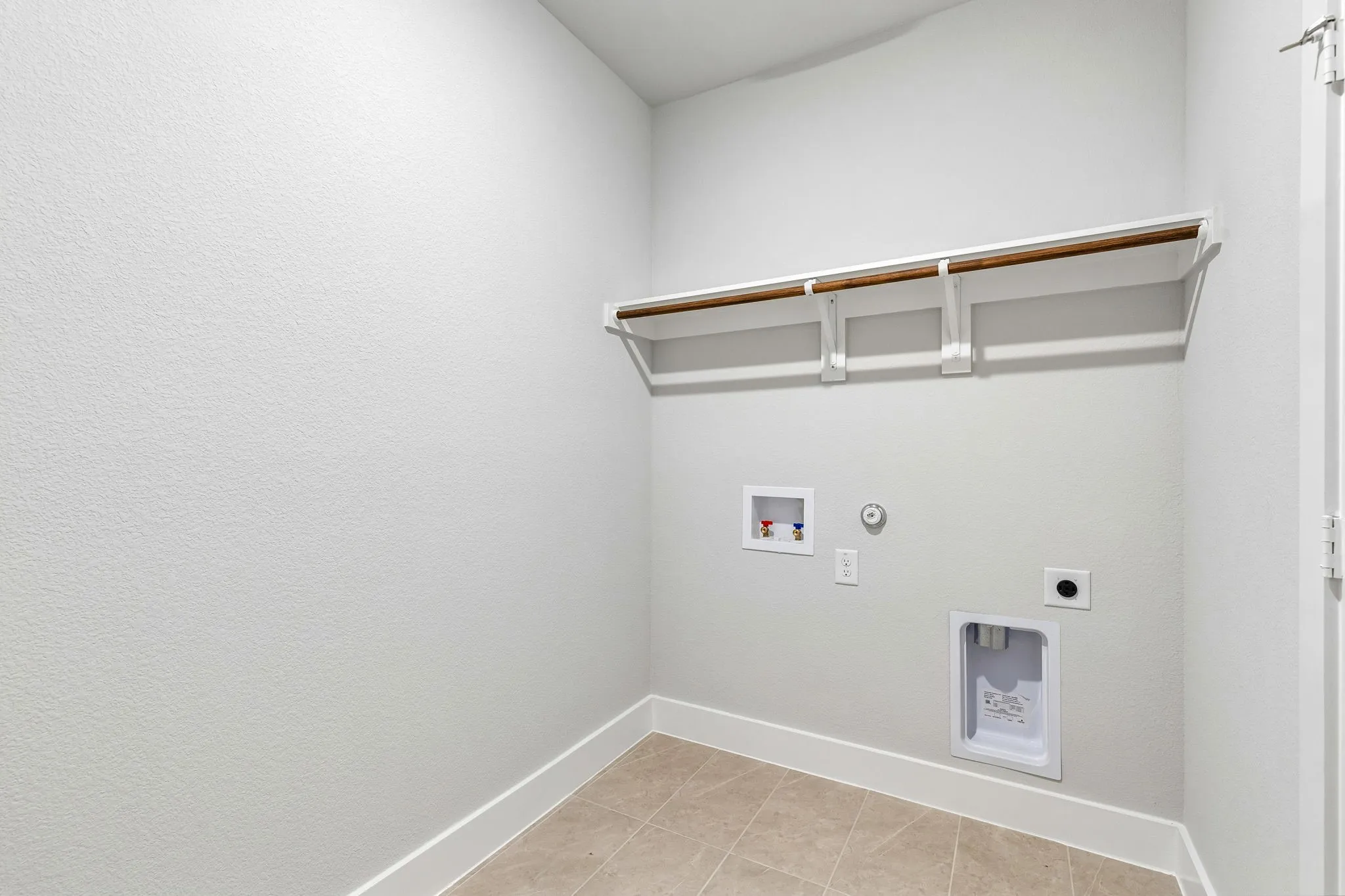 Utility room featuring tile flooring, a built-in hanging rod, and appliance hookups