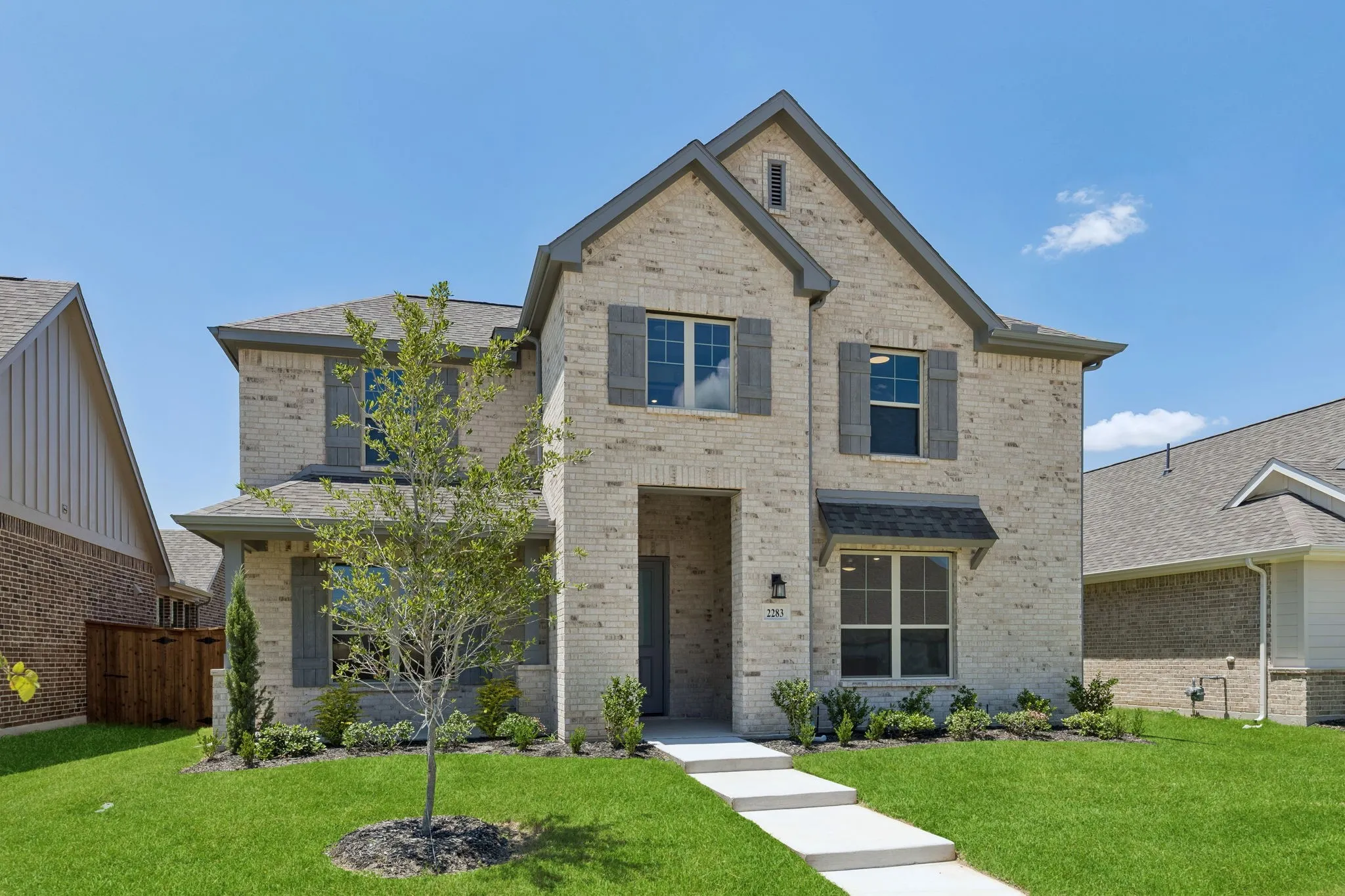 Two-story brick exterior with gabled roof lines, dark shutters, and a covered entry