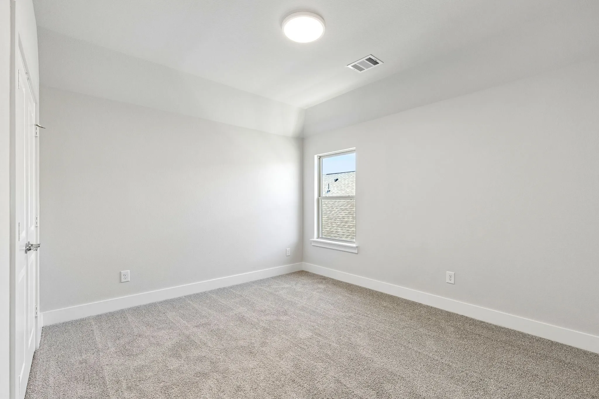 Vaulted ceiling with an overhead light fixture, light gray carpet flooring, white trim, and a window with white casing