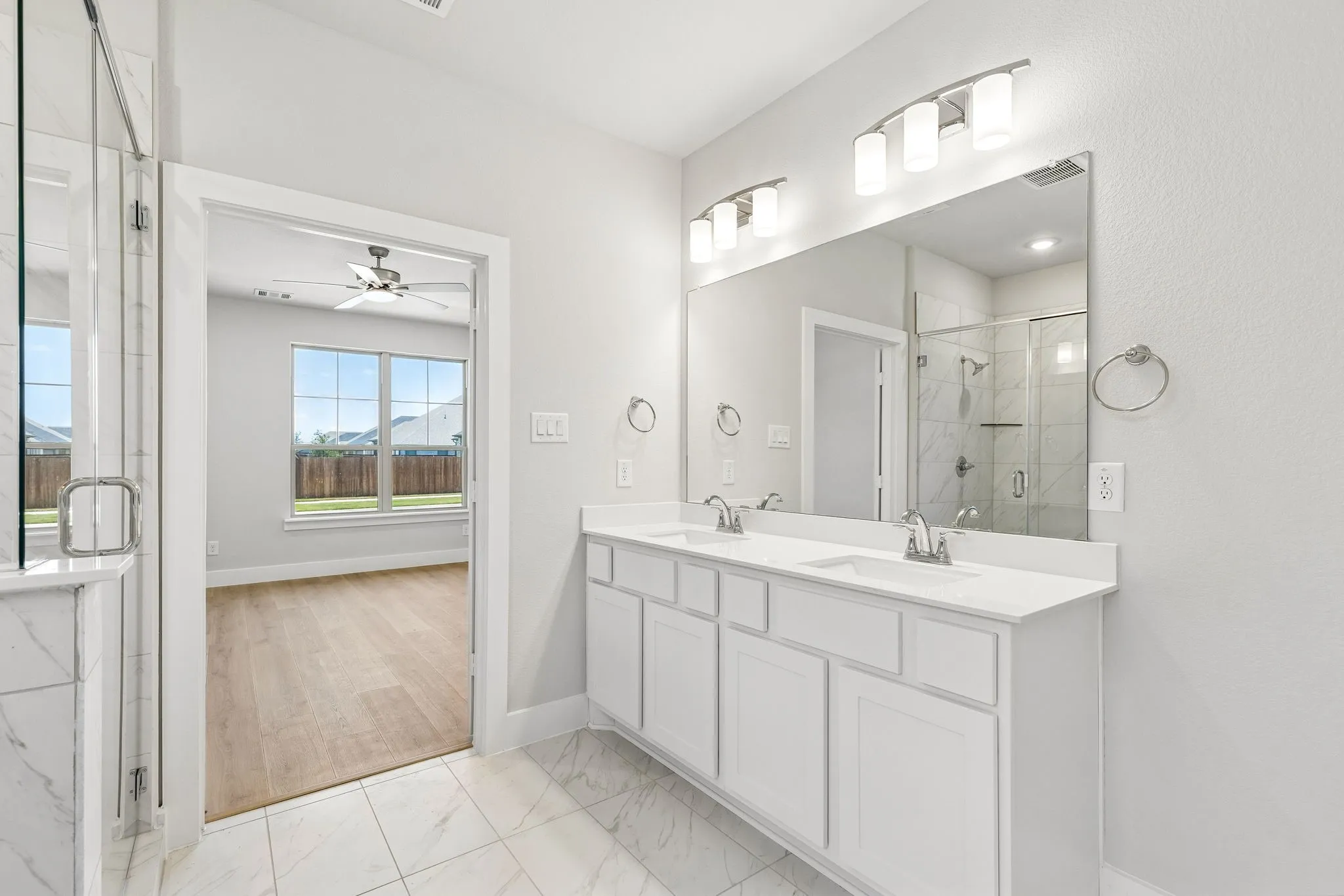 Dual sink vanity with white cabinetry, a large mirror, and overhead lighting