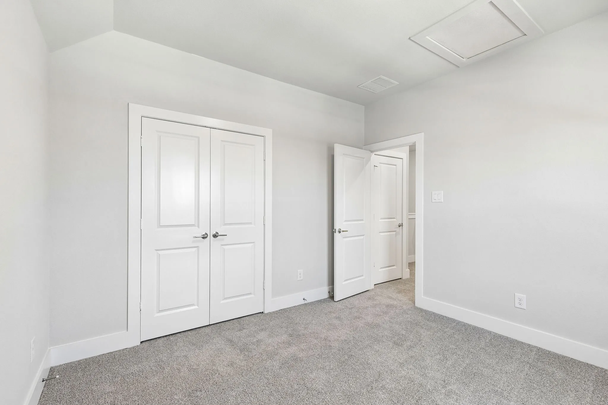 Neutral wall color, gray carpet, white trim, white paneled doors, and ceiling access panel