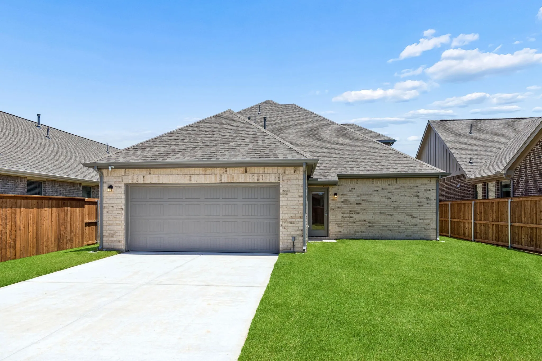 Brick exterior with a two-car garage, concrete driveway, and a shingle roof