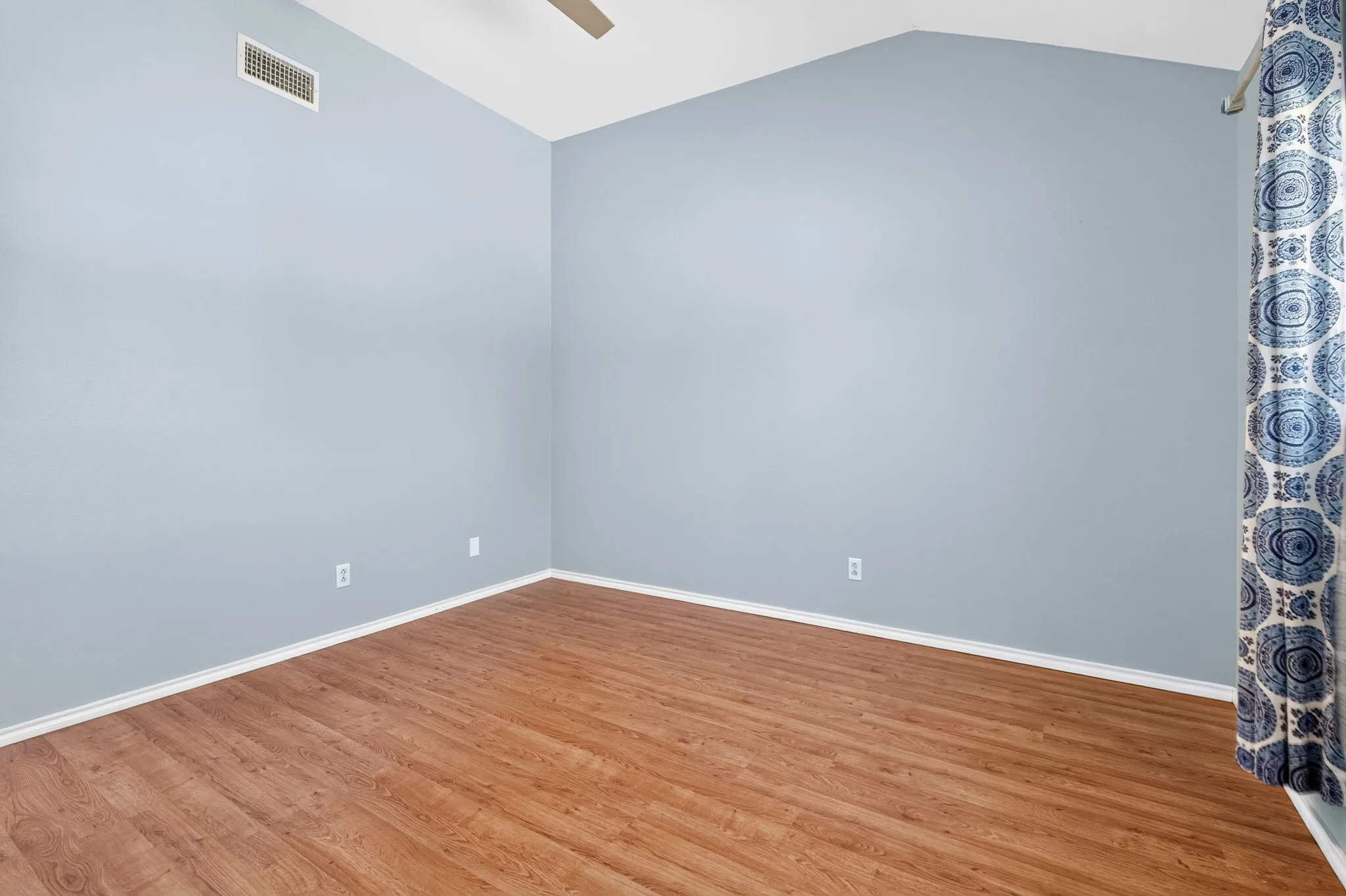 Ceiling fan, wood-finish LVP flooring, and light blue painted walls.