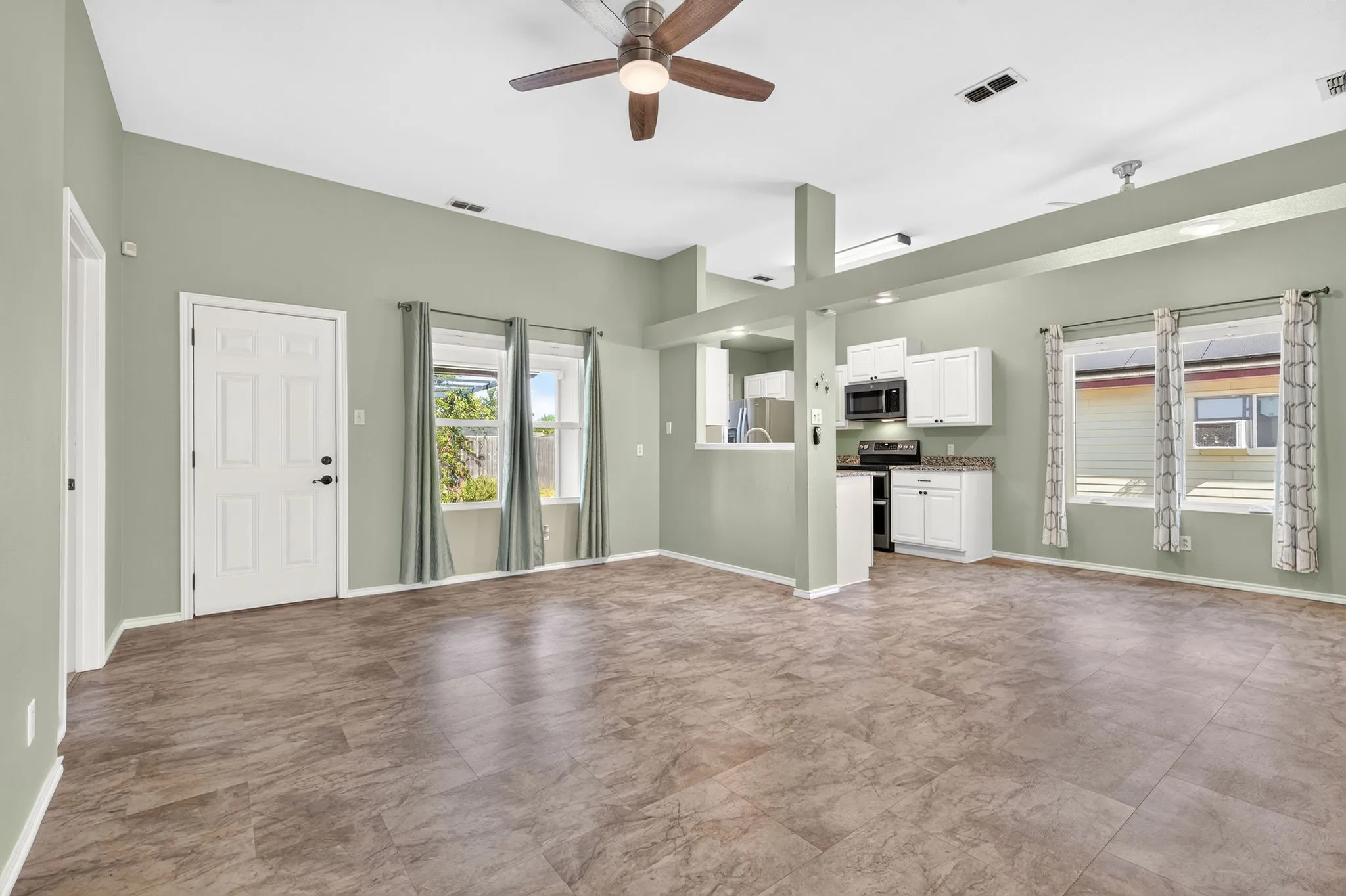 Spacious open-concept living area featuring high ceilings flowing into the dining and kitchen.
