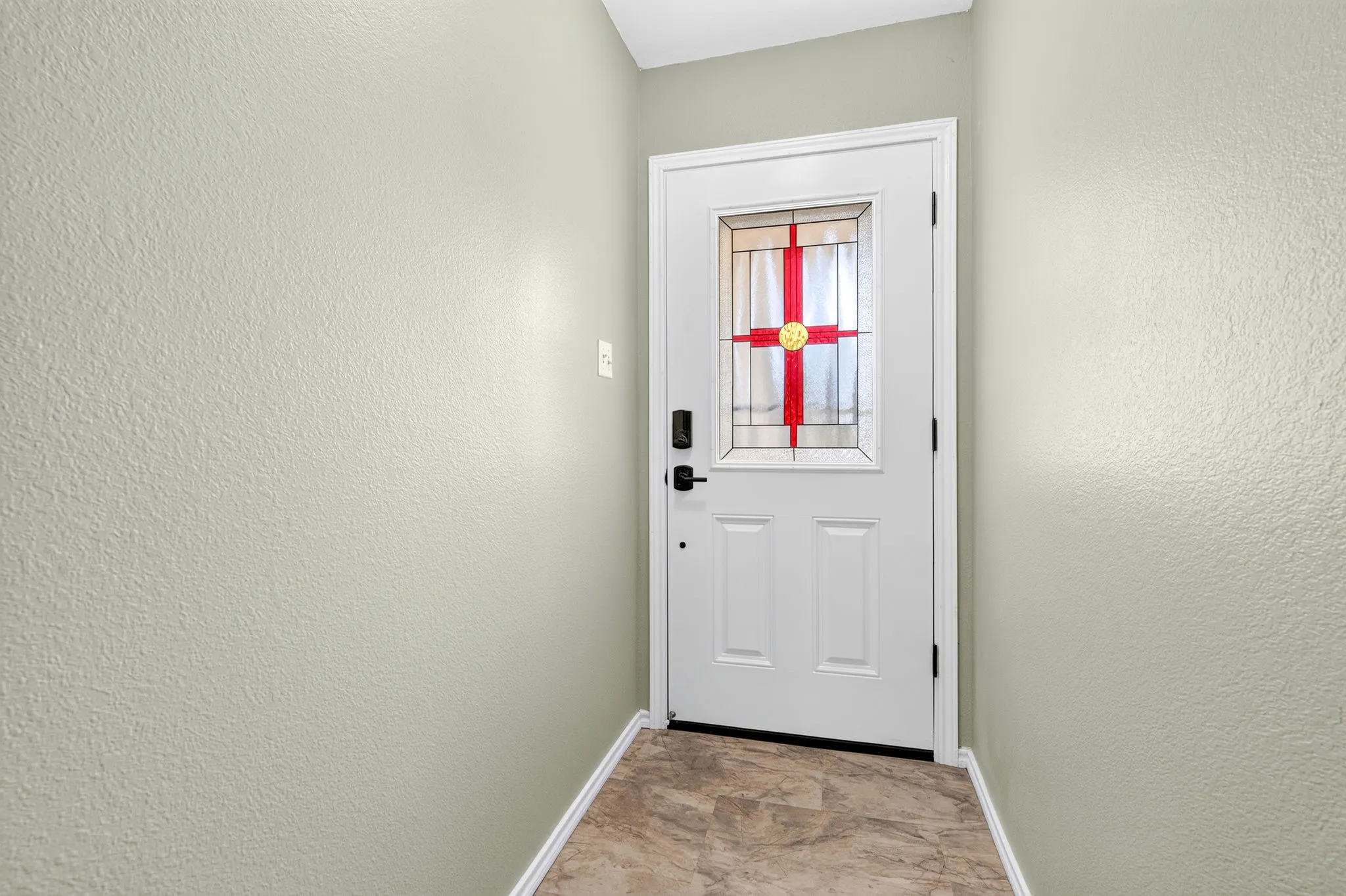 Entry door with stained glass insert with long entry way into living.