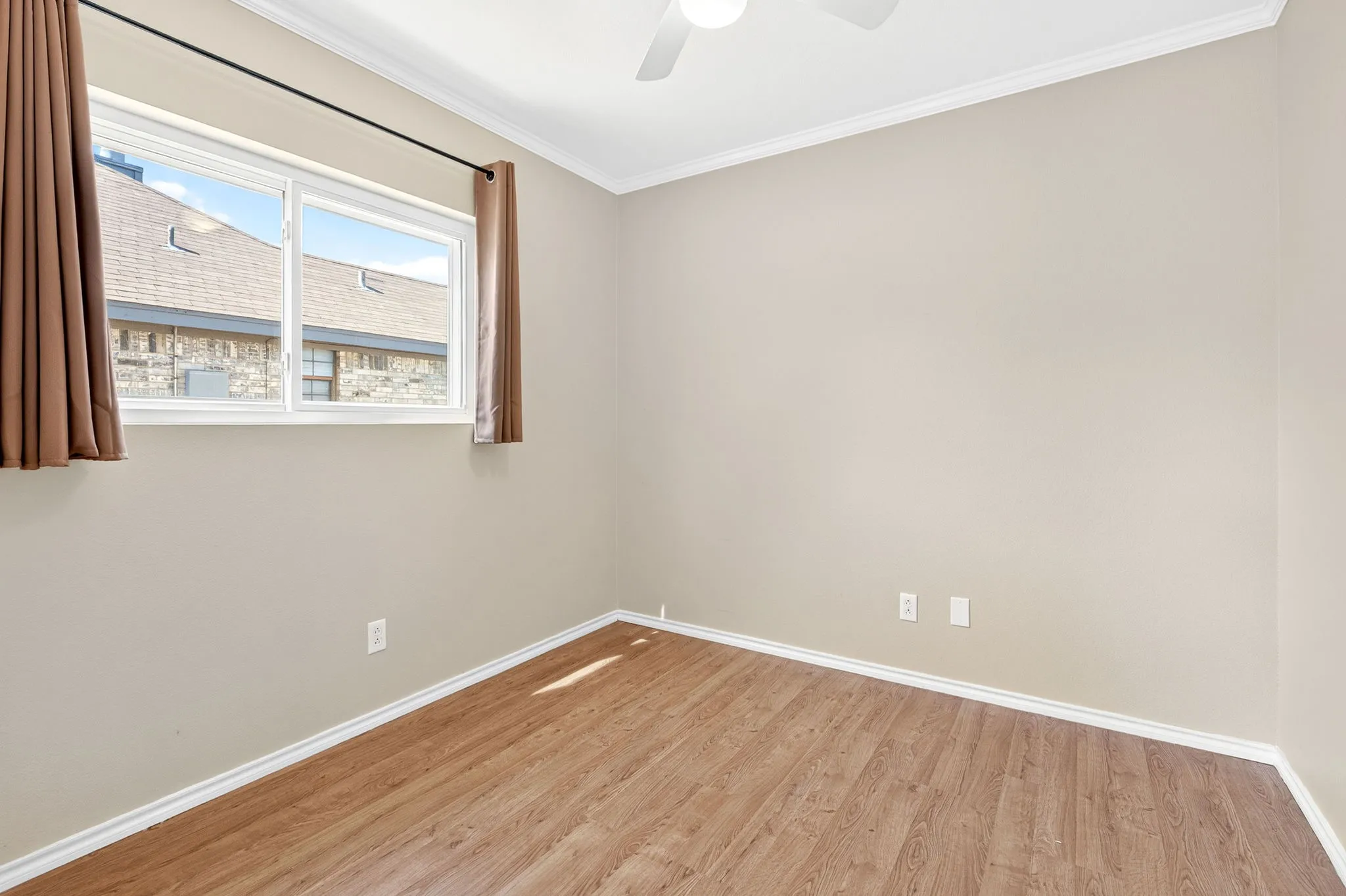 Wood-finish plank flooring, white trim, ceiling fan, and a double window in third bedroom.