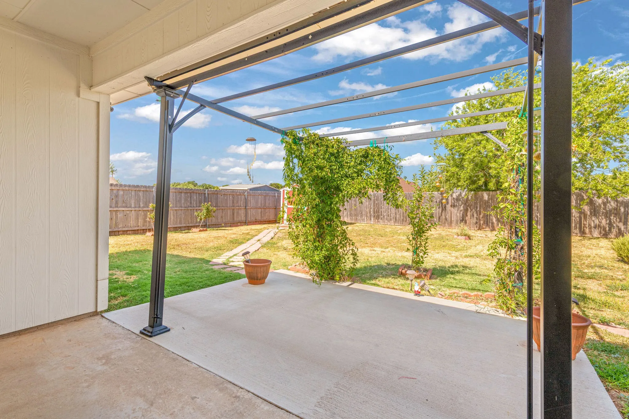 Concrete covered patio with an extended metal pergola structure.