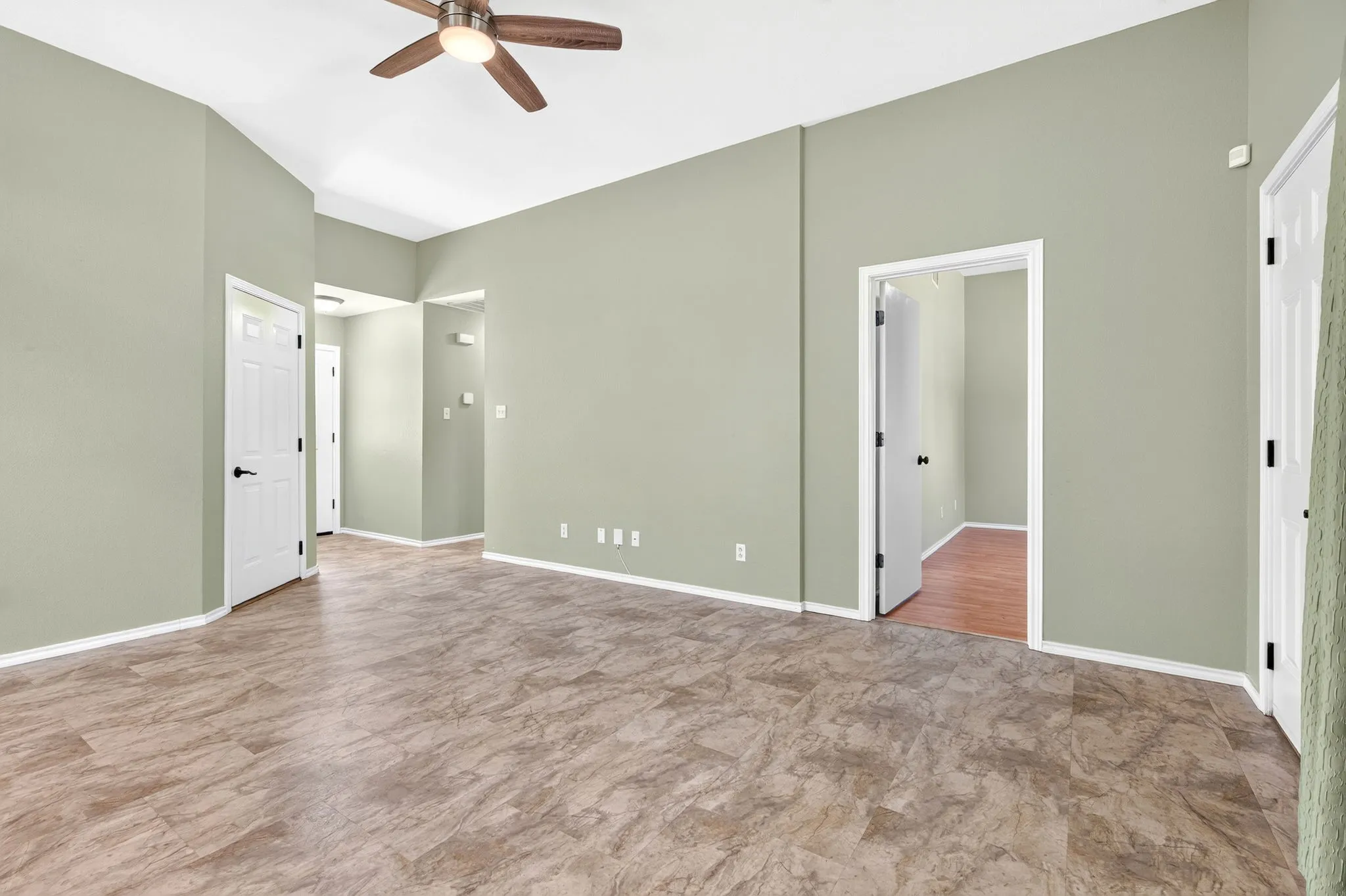 Living room offers high ceilings and a ceiling fan.  Front hallway leads to two bedrooms and a bath.  Primary suite enters off living room.