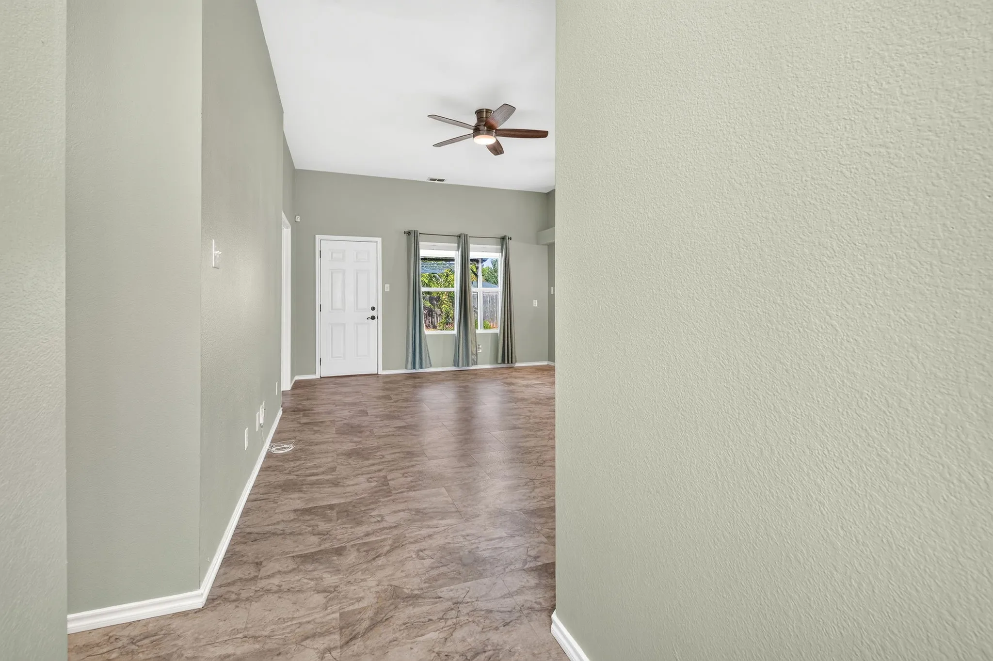 View from entry hallway into living room with back windows and door to back yard.