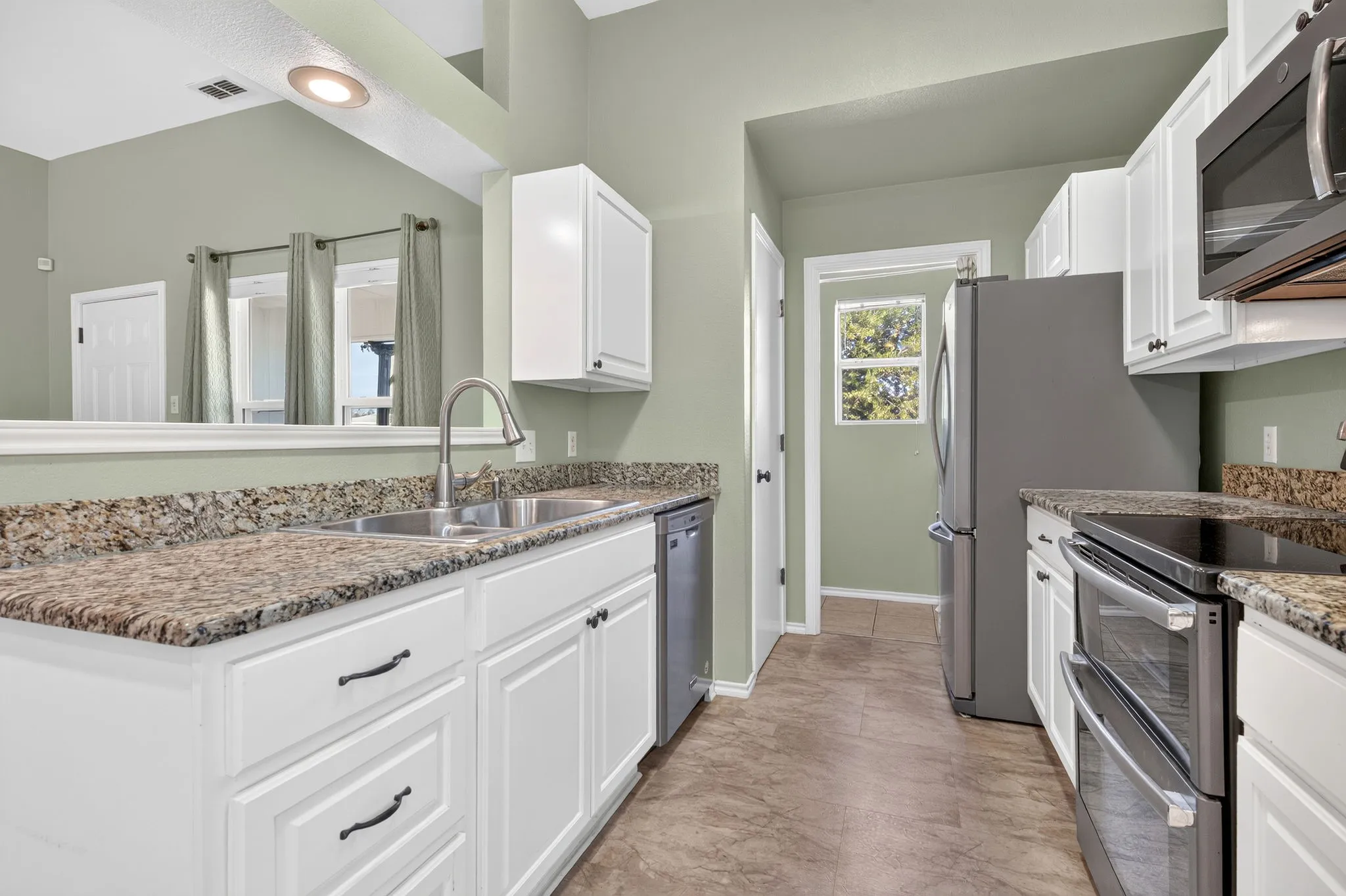Kitchen featuring white cabinetry, granite countertops, stainless steel appliances, and a double basin sink plus pantry.