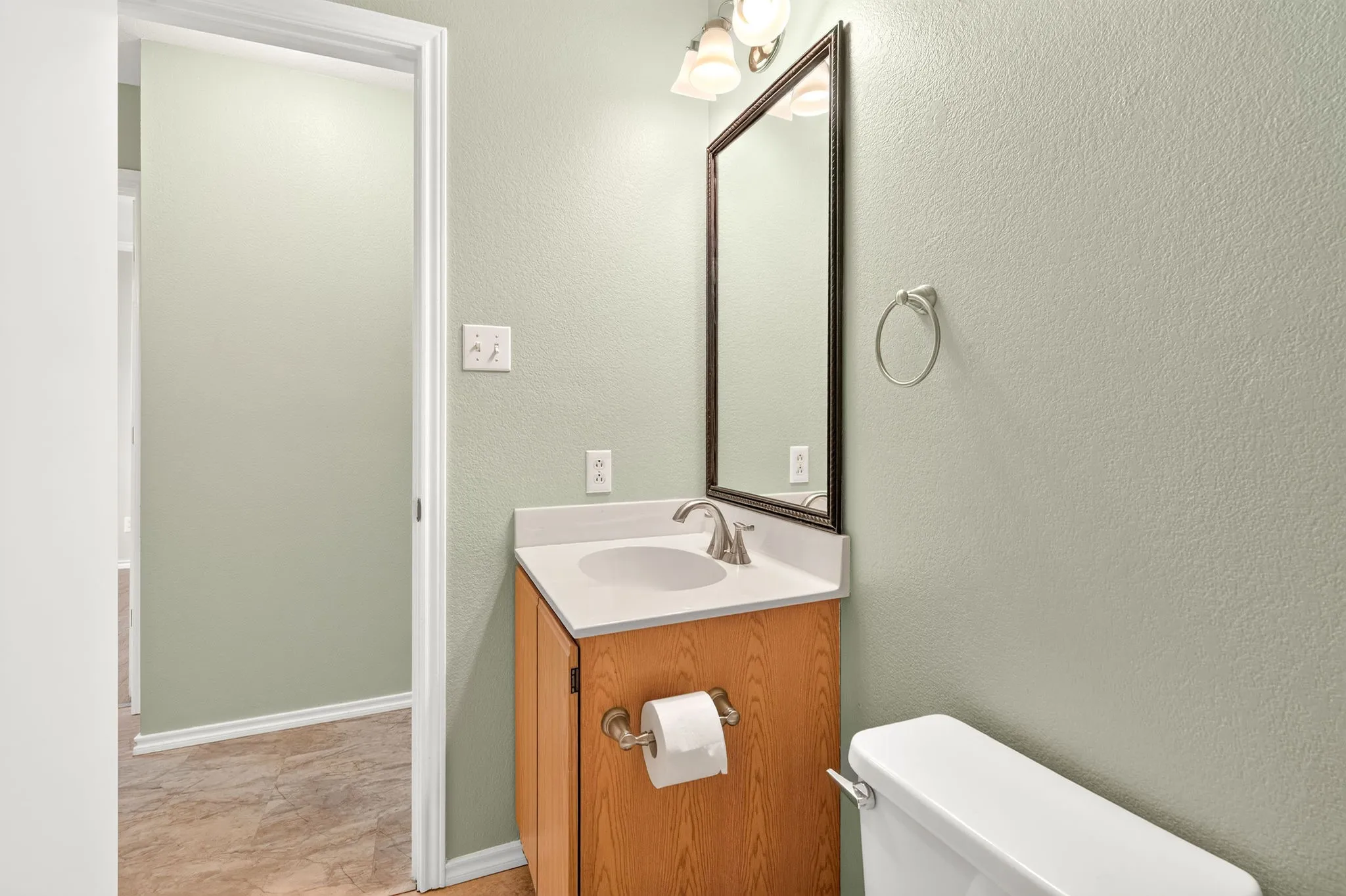 Bathroom vanity with a white countertop and sink, and wood-finish cabinetry.