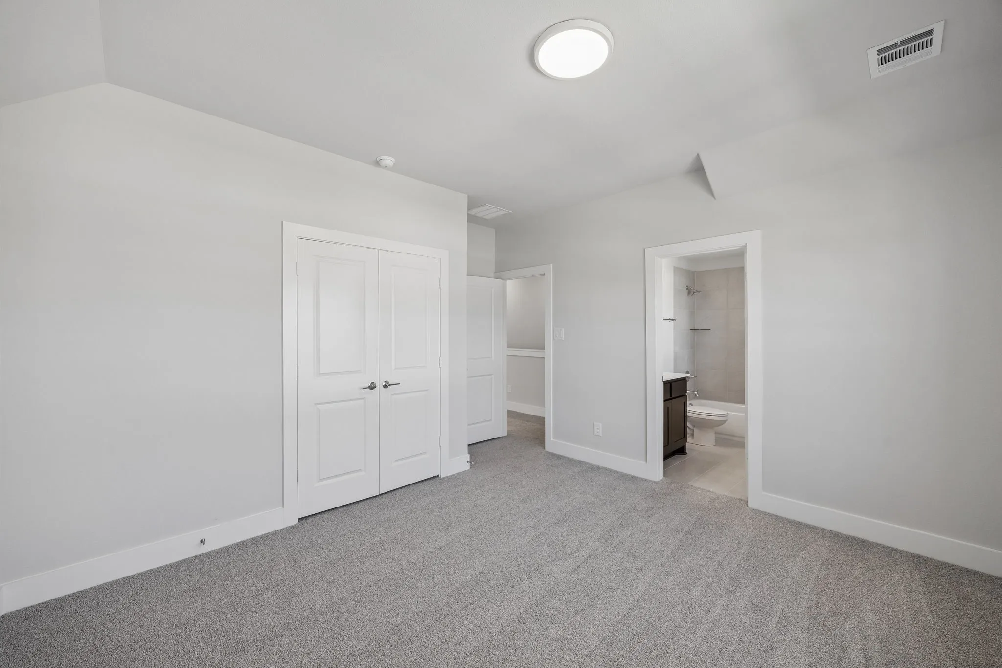 Neutral-toned walls complement plush grey carpeting