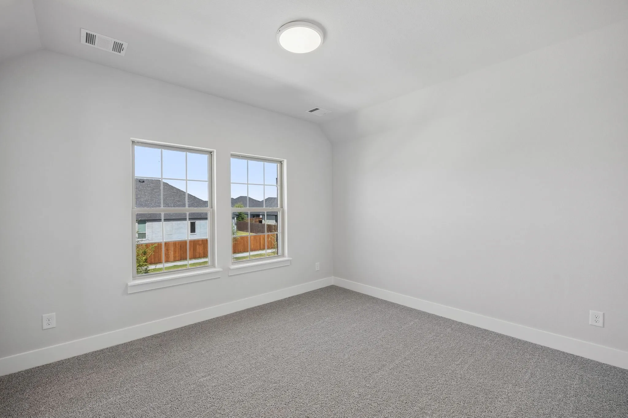 Neutral tone walls, two double-hung windows with grilles, and a flush mount ceiling light