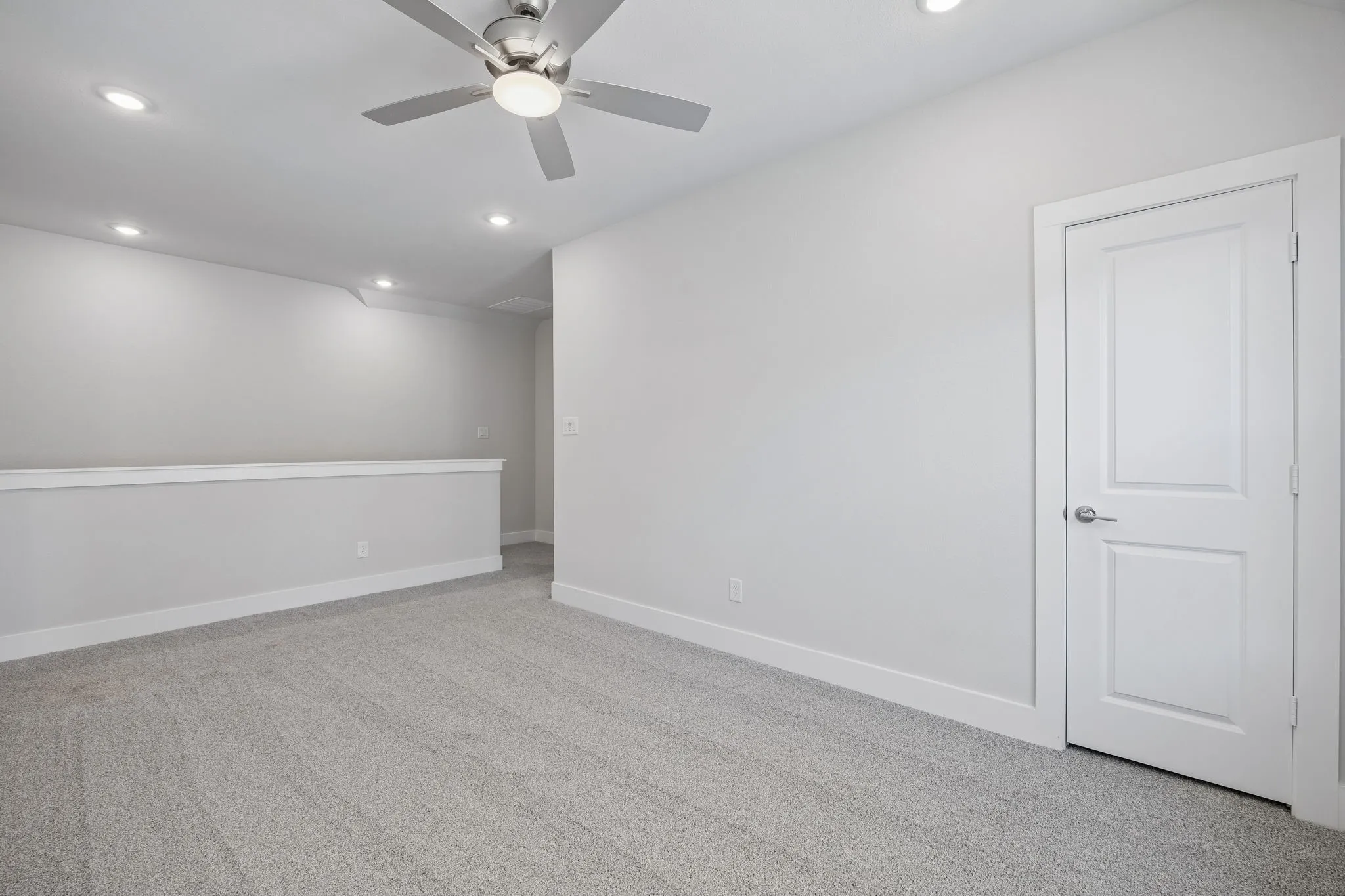 Carpeted flooring, contemporary ceiling fan, recessed lighting, white interior door, and a half-wall partition