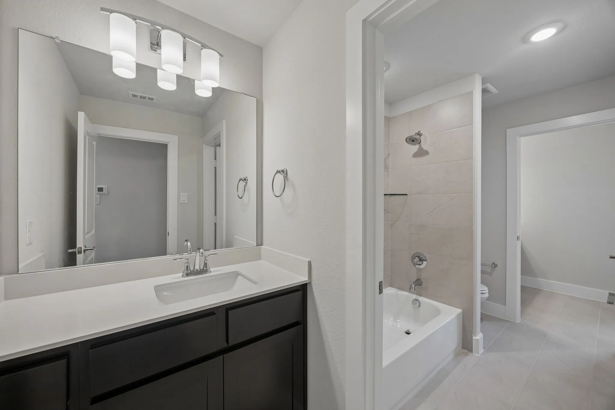 Vanity with an integrated rectangular sink, stone countertop, and four-light fixture