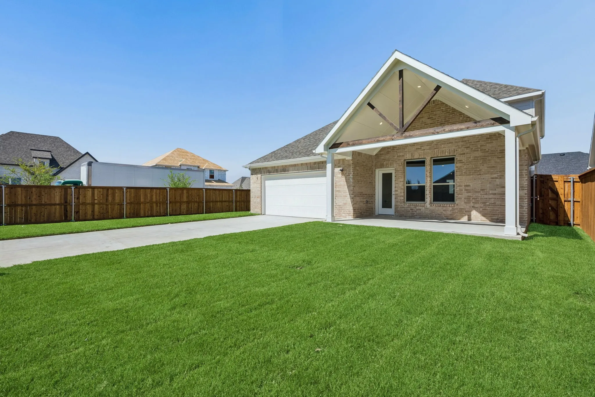 Expansive backyard with a manicured lawn, full wood fencing, and a concrete patio
