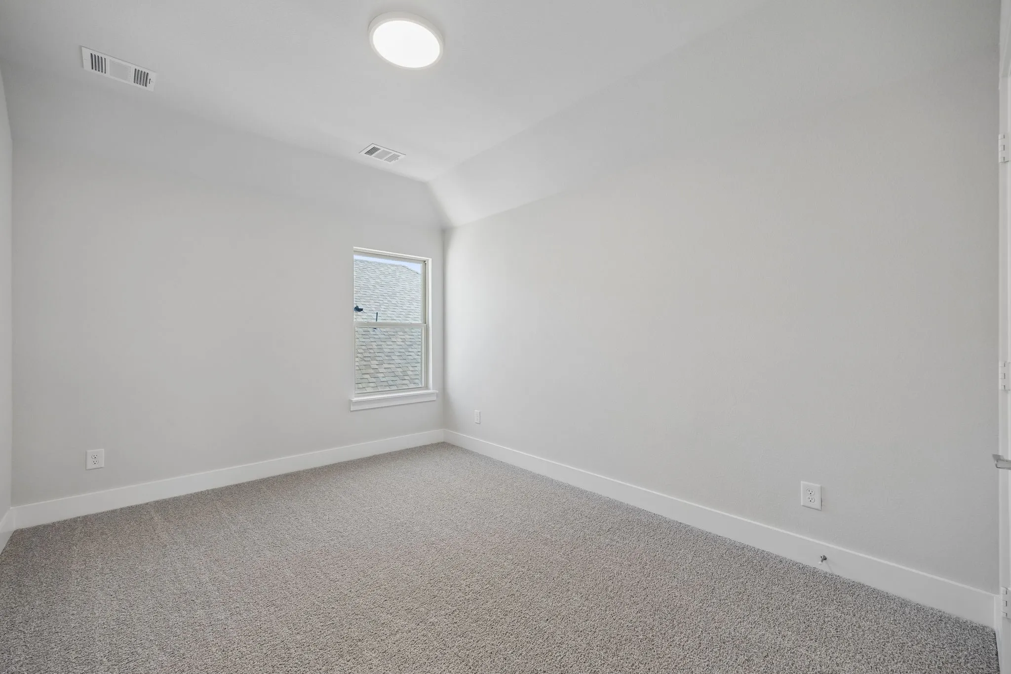 Vaulted ceiling featuring a flush-mount light fixture, a window with white trim, and light grey carpeting