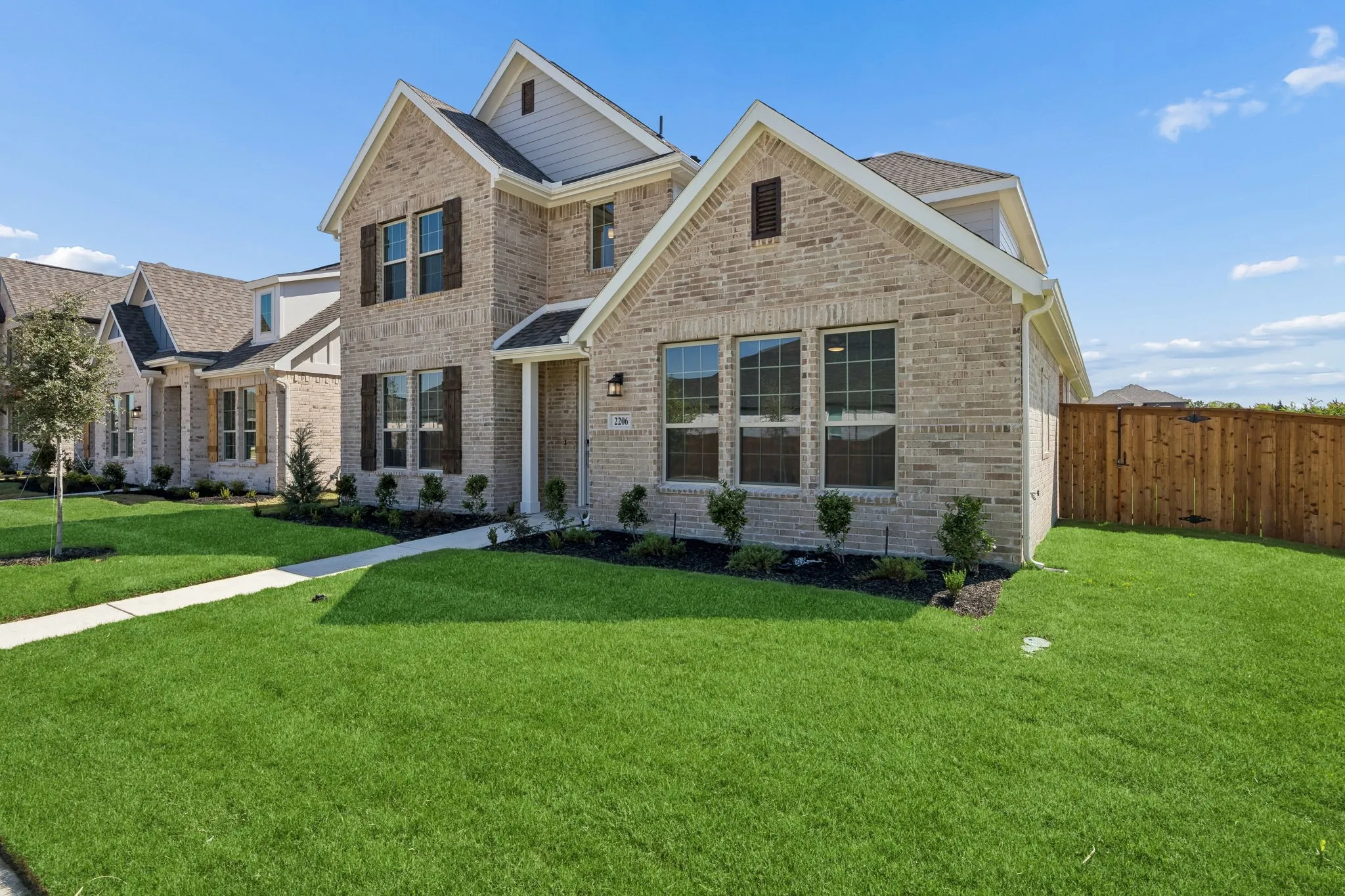 Brick exterior with gables, multiple windows, and a manicured lawn