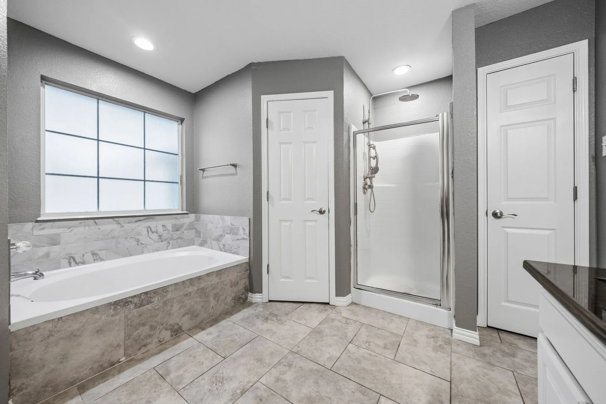 Recessed lighting, tile flooring, glass-enclosed shower, built-in bathtub, and a window with privacy grid