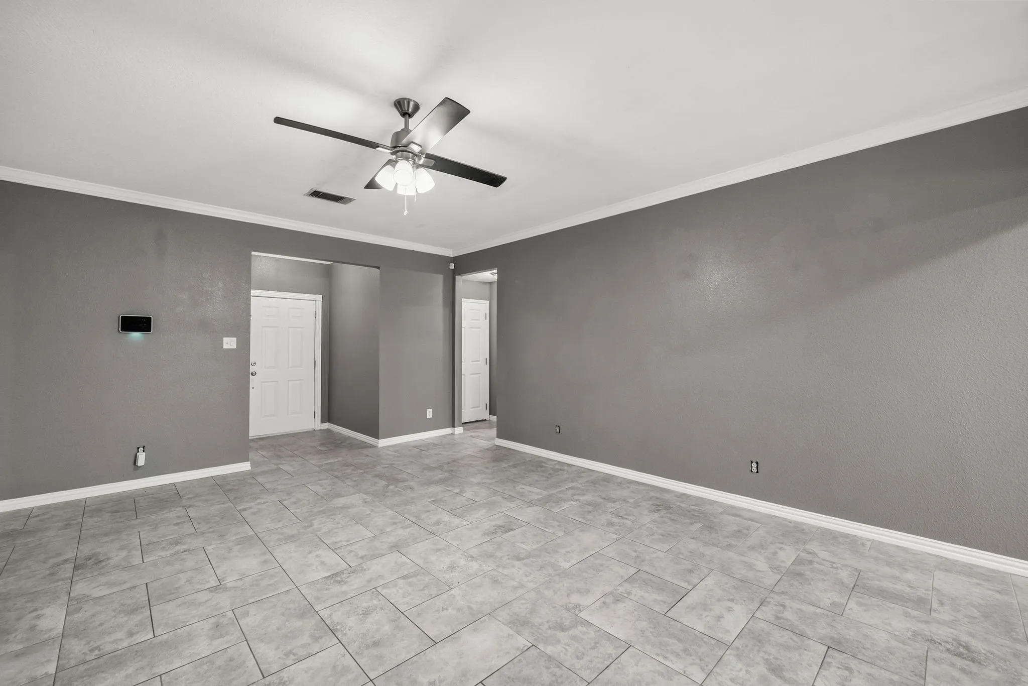 Spacious room featuring tile flooring, neutral wall tones, white trim, and a ceiling fan with integrated lighting