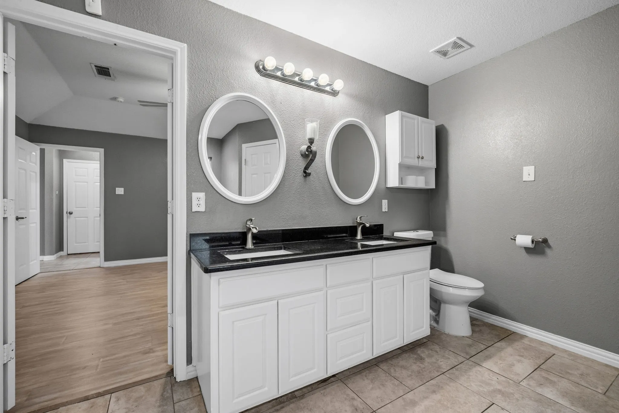 Dual vanity with white cabinetry, dark countertop, and undermount sinks
