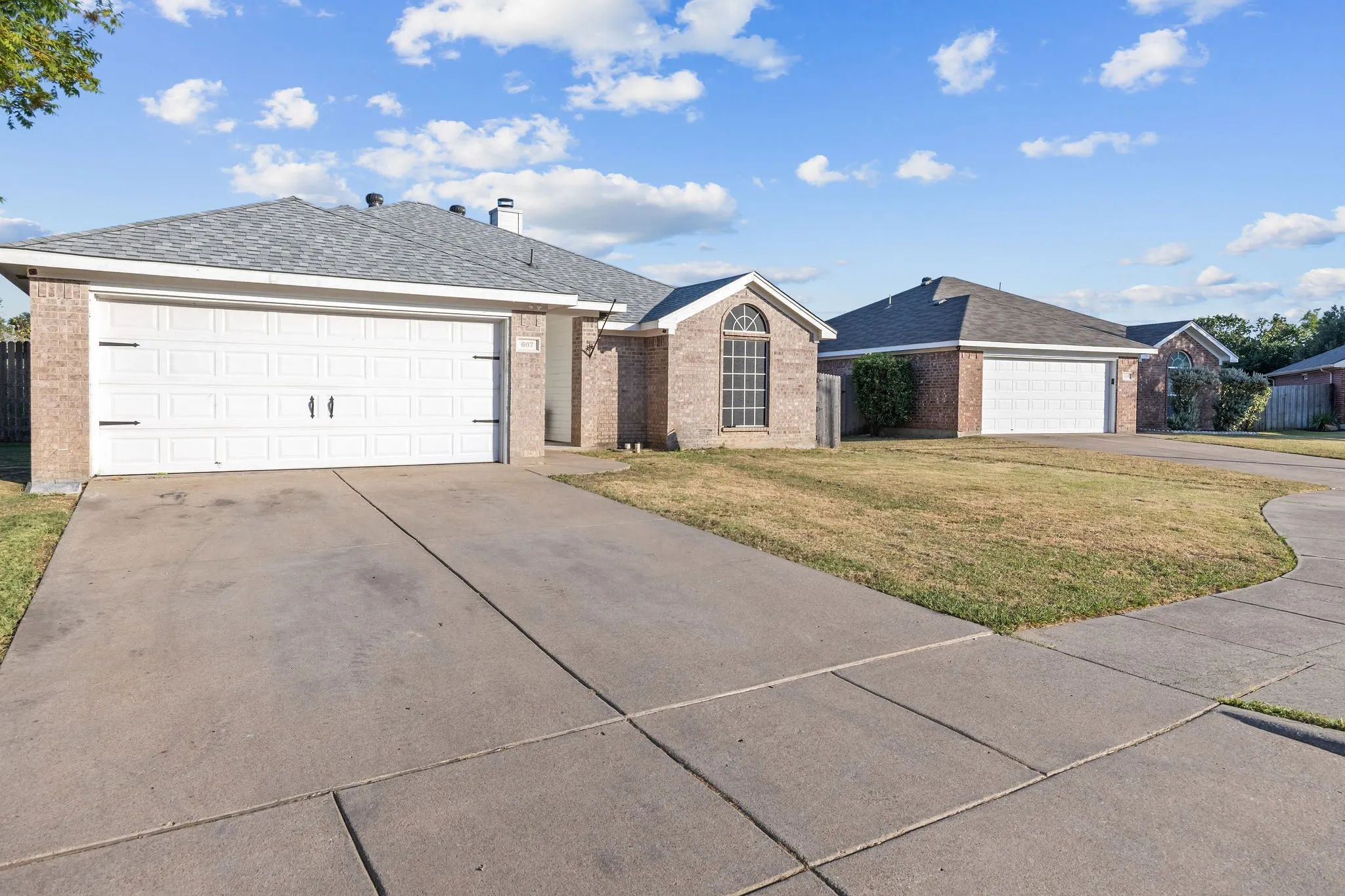 Brick exterior with an arched window, two-car garage, and concrete driveway