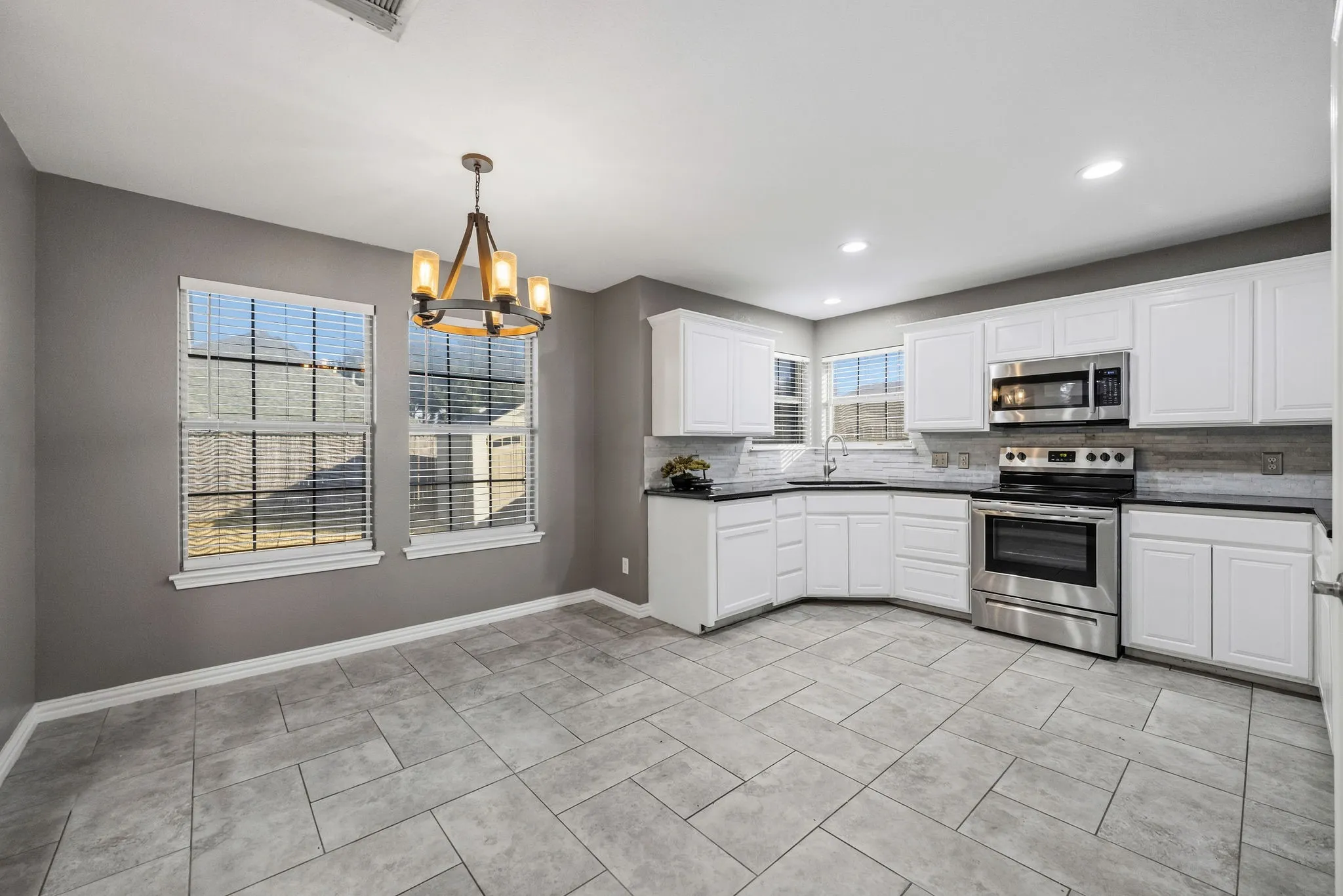 Kitchen with white cabinetry, dark countertops, a tile backsplash, and stainless steel appliances