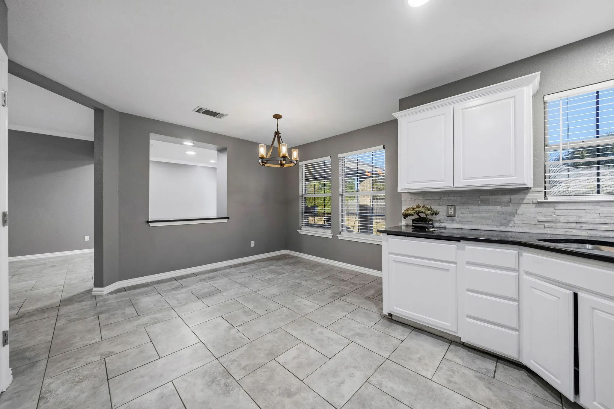 Kitchen with white cabinetry, black countertops, and a tiled backsplash