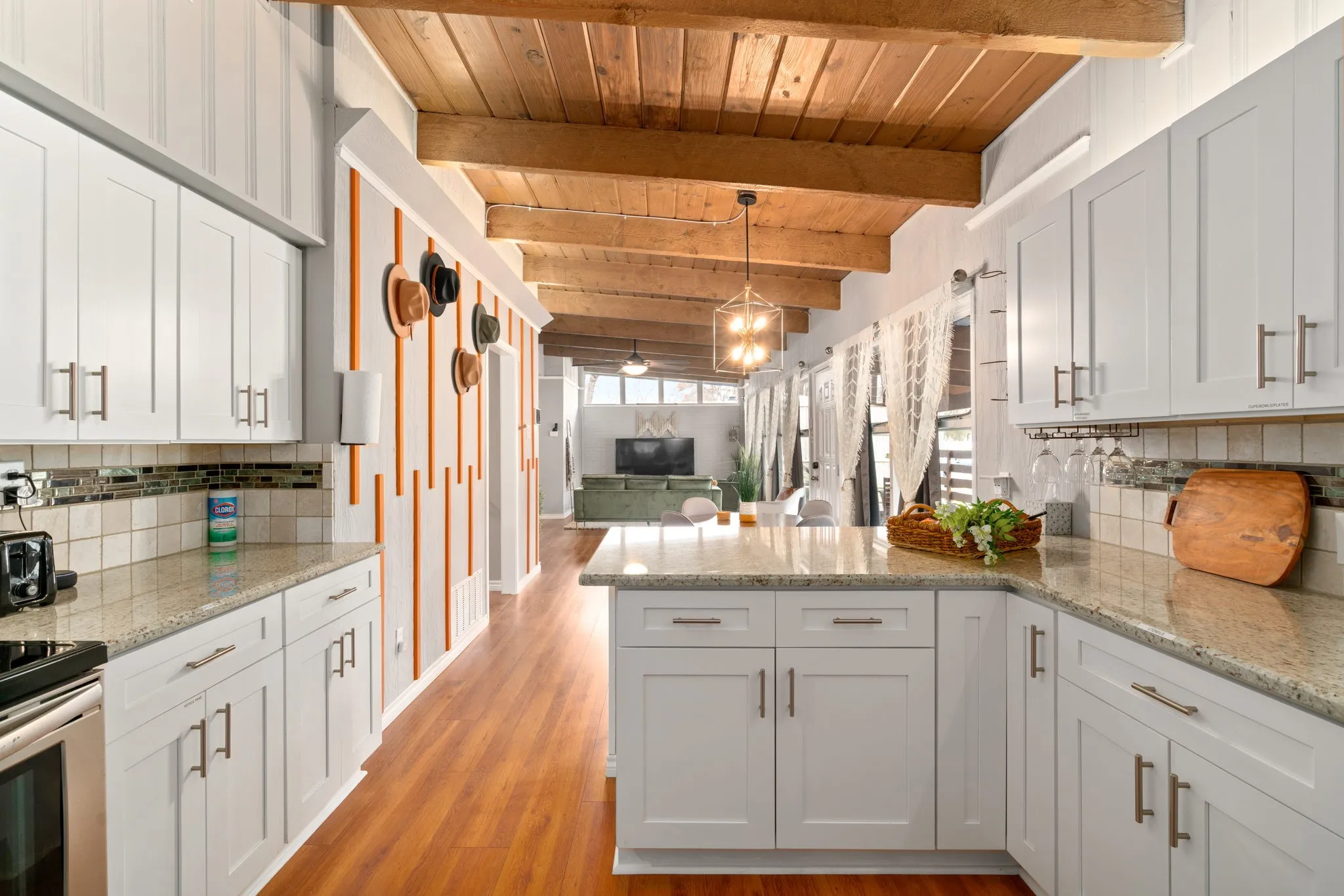 White shaker-style cabinetry with brushed nickel hardware, light-toned granite countertops, wood-finish flooring, a tiled backsplash, and exposed wood beam ceiling