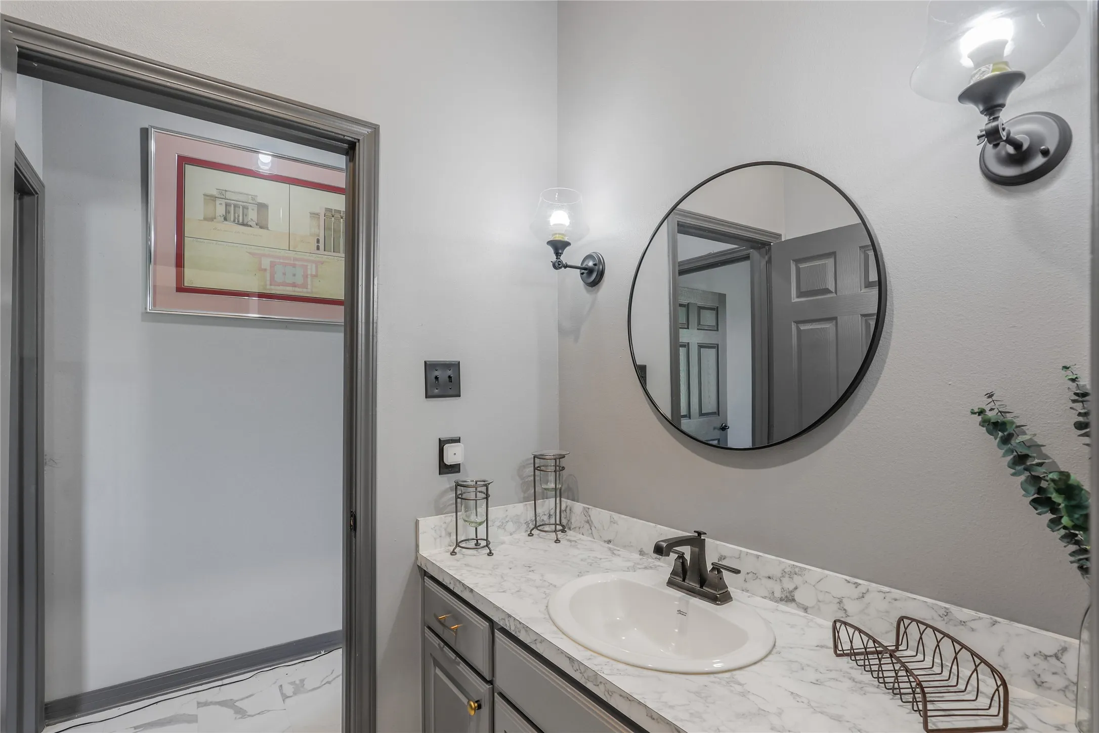 Vanity with a white oval sink, dark bronze faucet, and a stone-finish countertop