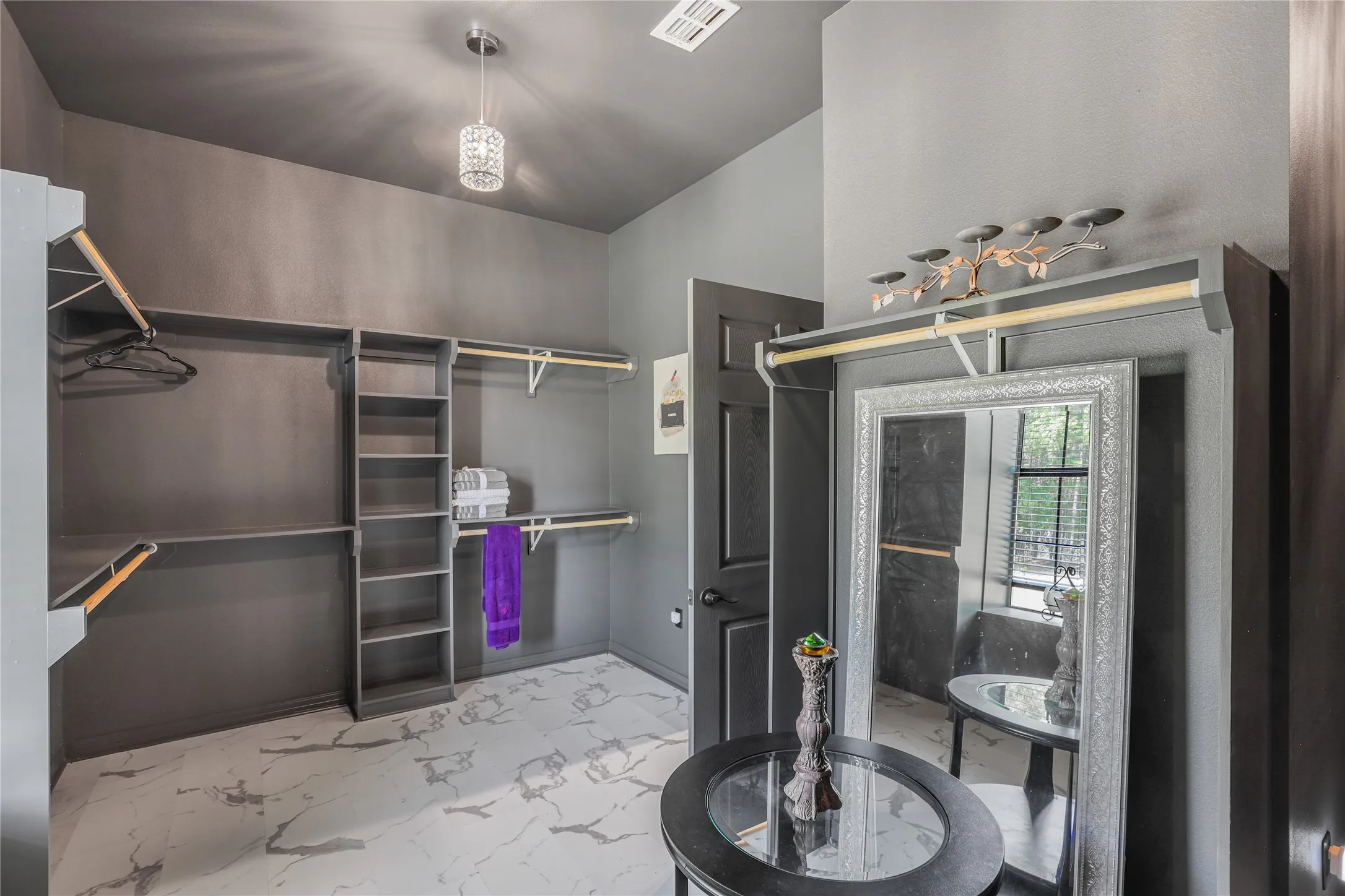 Built-in shelving and hanging rods, patterned tile flooring, and a crystal pendant light fixture