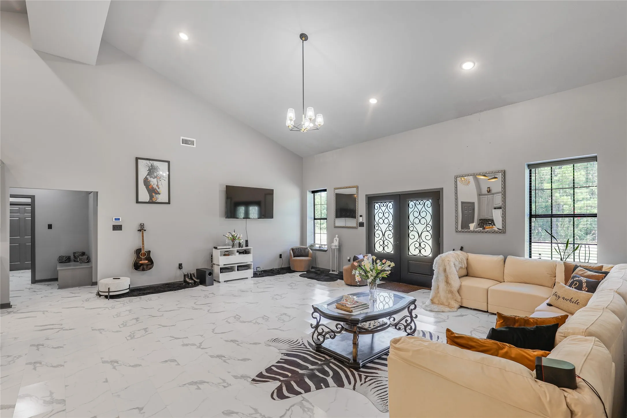 Vaulted ceilings, recessed lighting, double entry doors with decorative ironwork, large windows, and large-format floor tiling