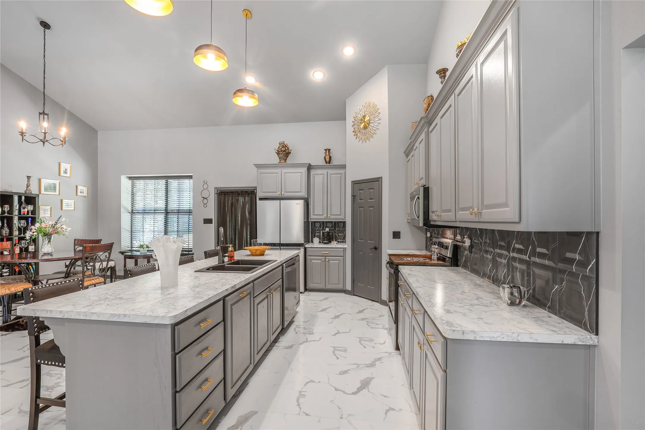 Vaulted ceiling, recessed lighting, central island with an undermount sink, grey cabinetry, and white countertops