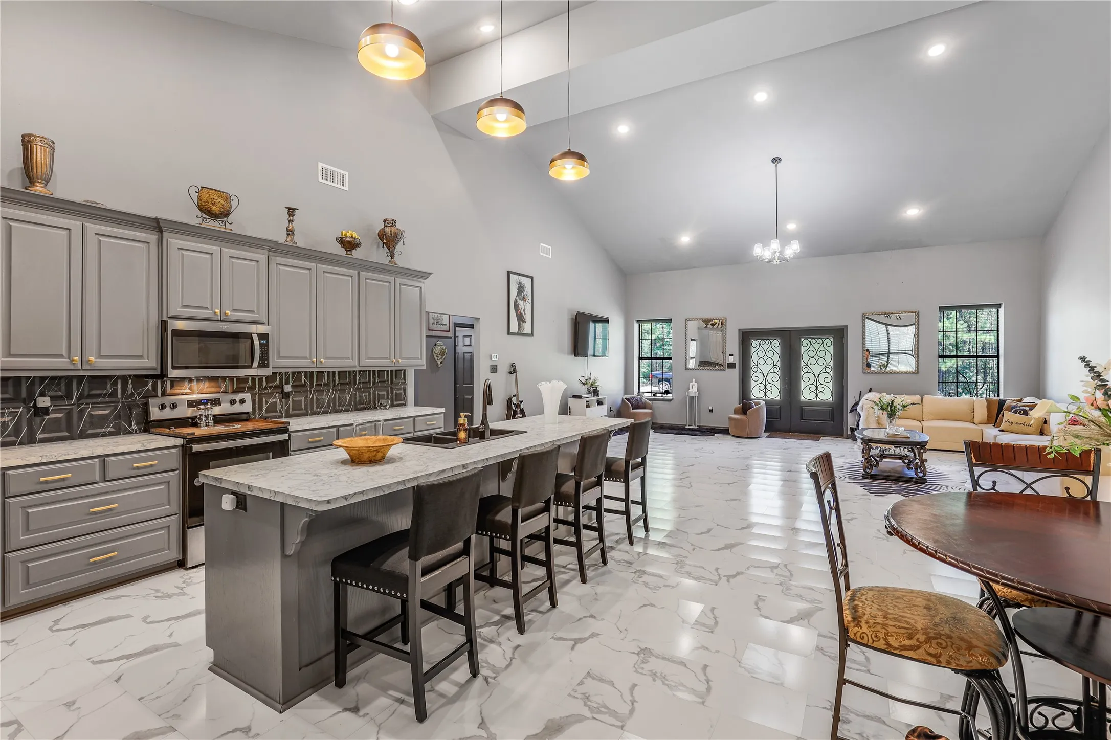 Vaulted ceilings with recessed lighting, kitchen island with seating, stainless steel appliances, marble-finish flooring, and double entry doors