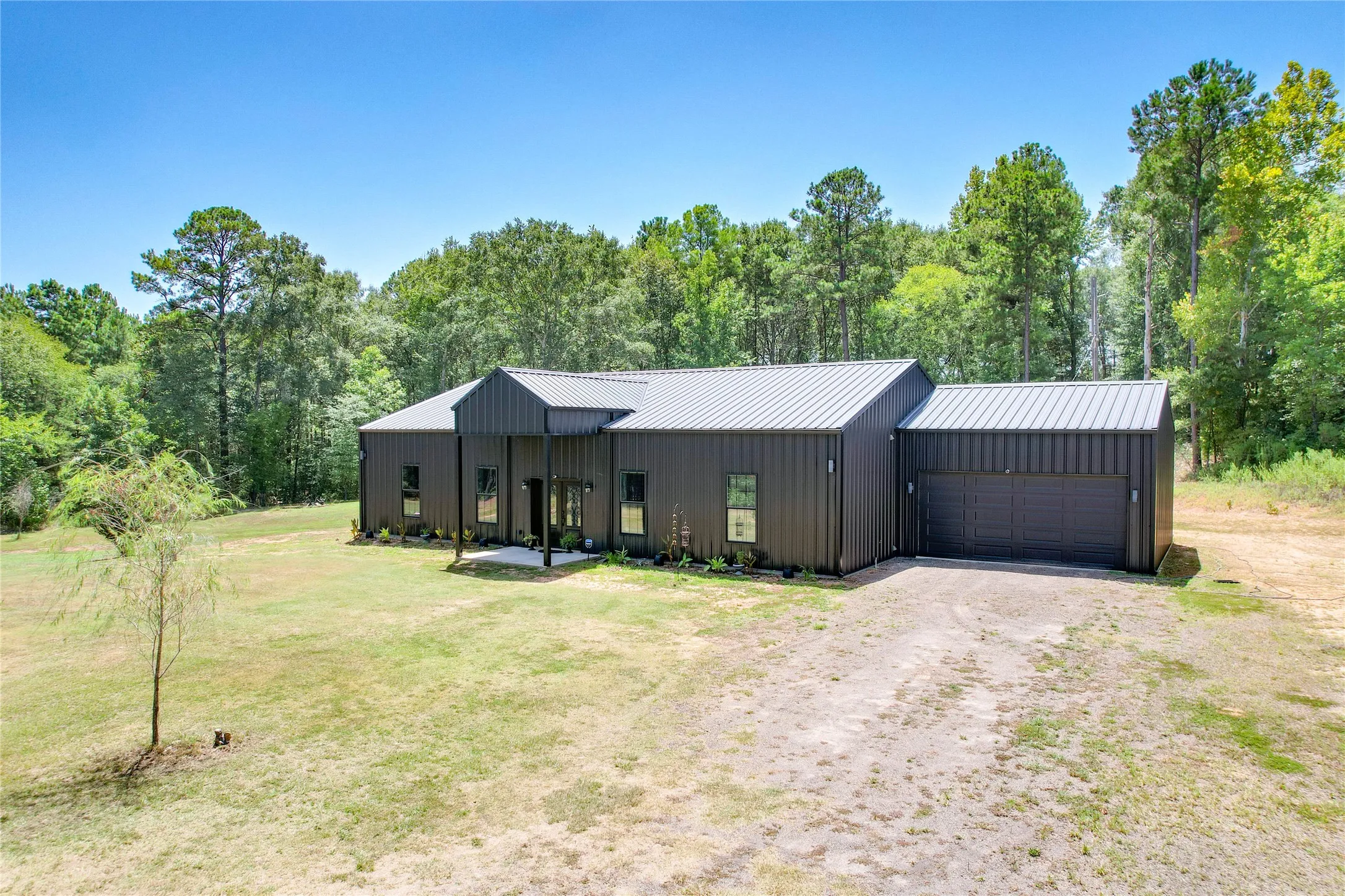 Modern exterior with metal siding, gabled metal roof, covered entry, and attached garage