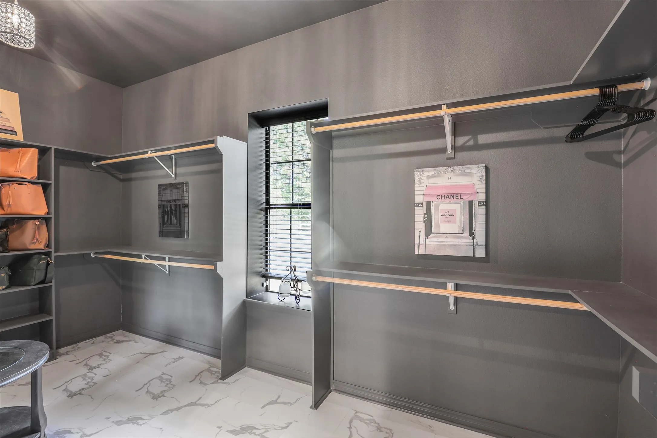 White and grey marble-look flooring, built-in shelving, two levels of hanging rods, and a window with blinds