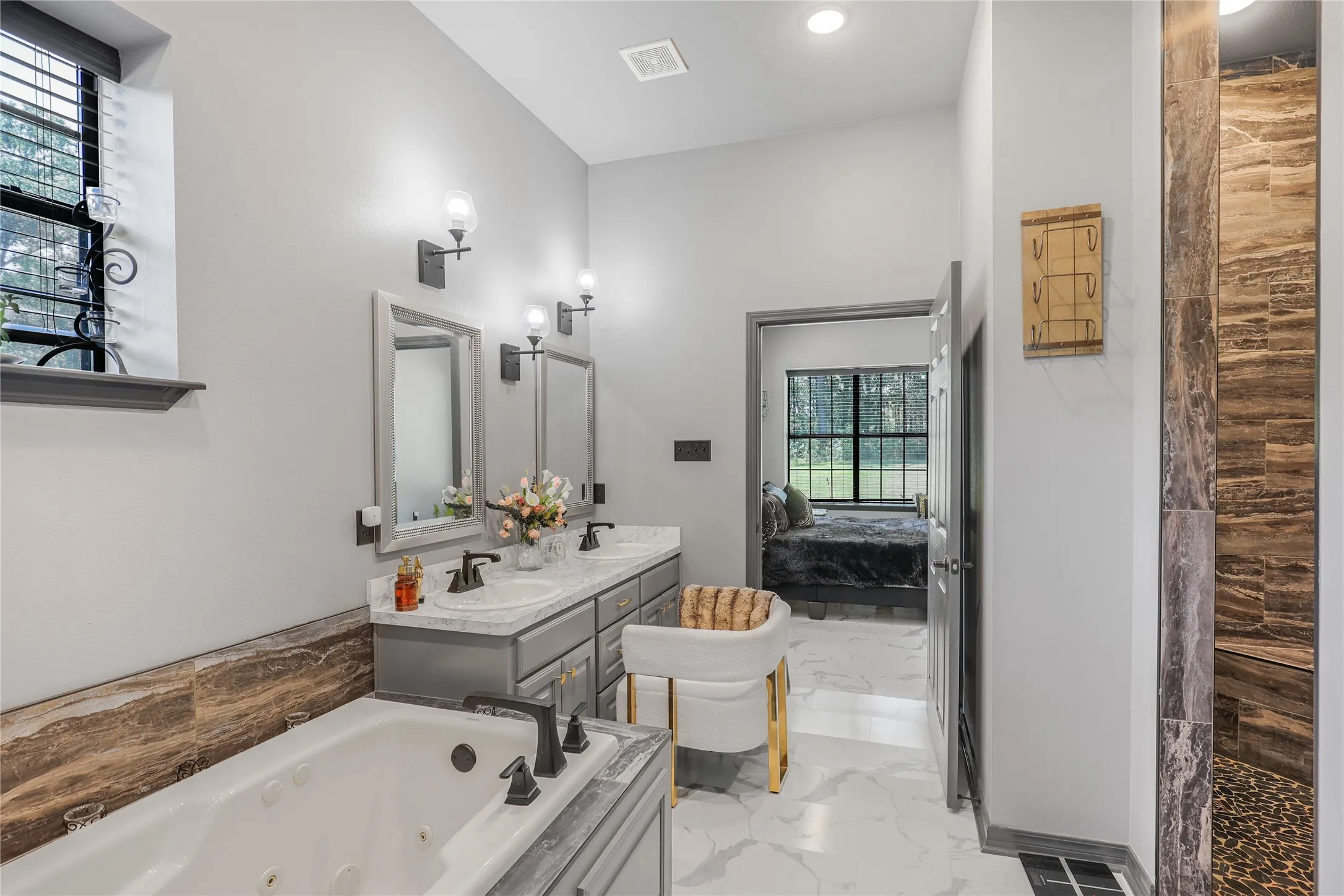 Dual vanity with undermount sinks, separate soaking tub with jets, and a walk-in shower with textured tile and a stone floor