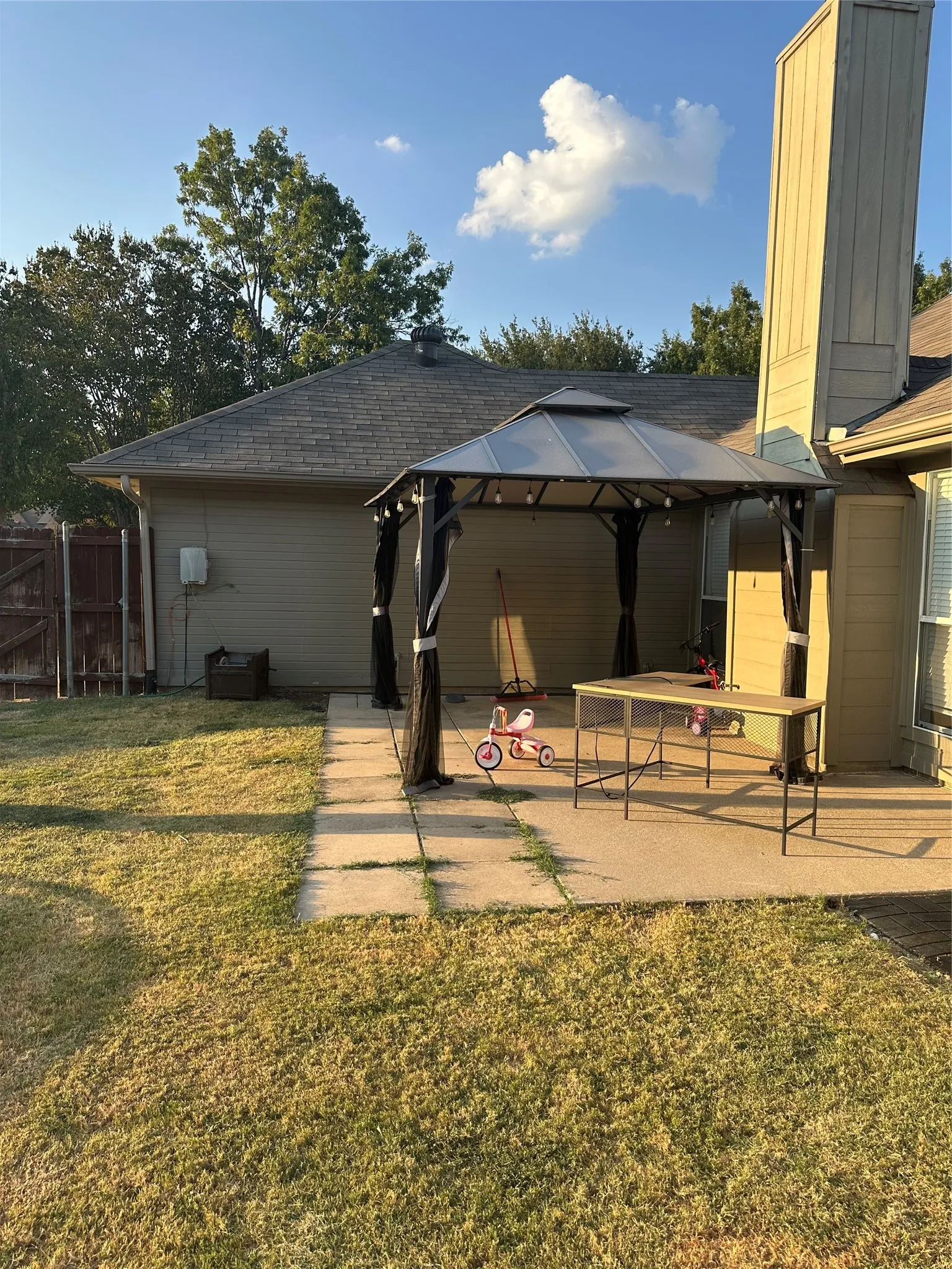 Expansive backyard with a concrete patio, covered gazebo, and a rectangular outdoor bar