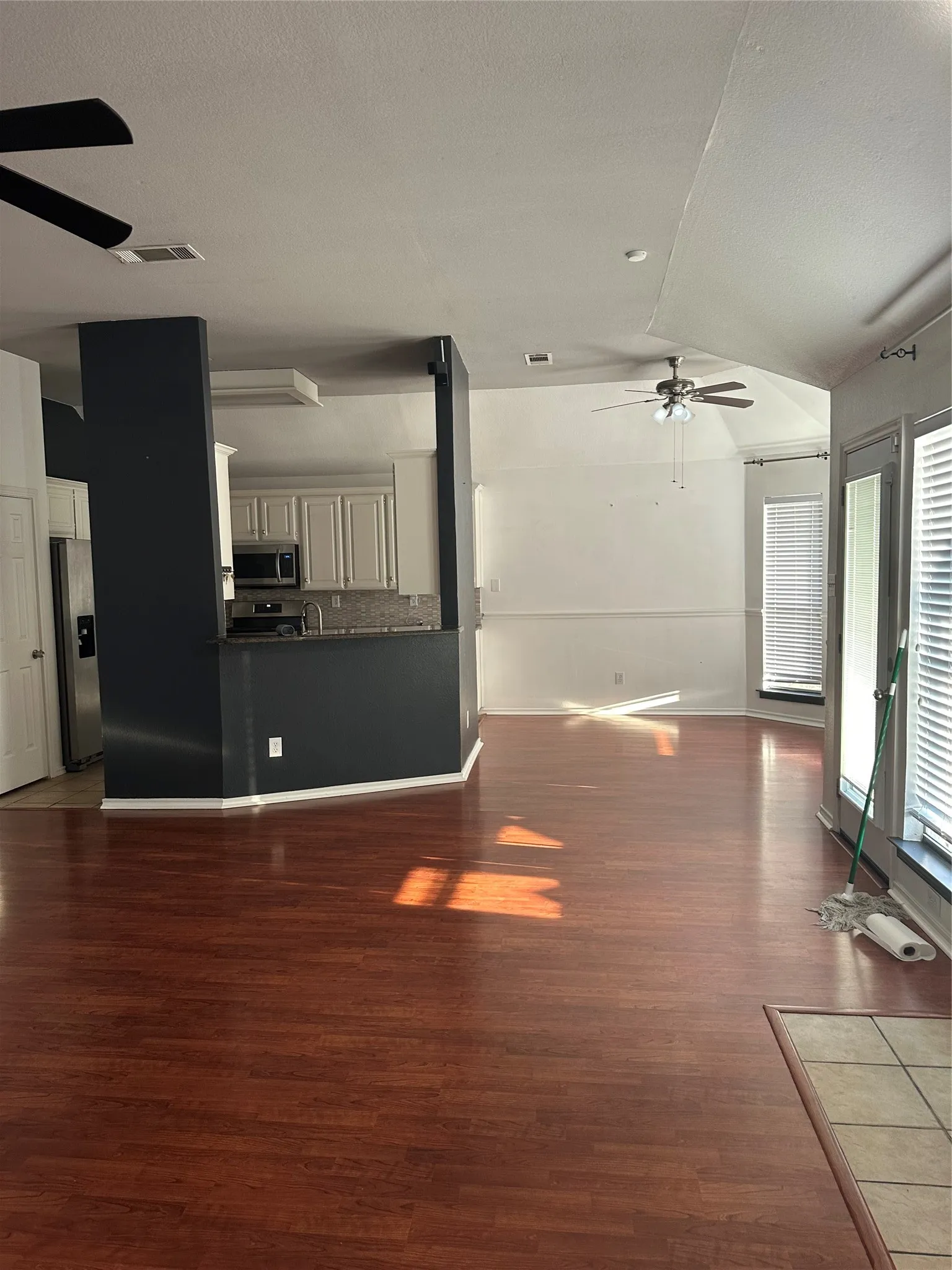 Wood-finish flooring throughout, kitchen with light cabinetry, stainless steel appliances, and a tiled backsplash