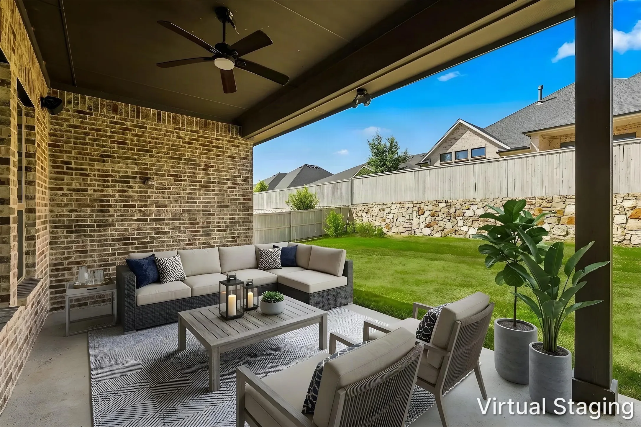 Covered patio with a dark wood-finish ceiling fan, brick accent wall, and concrete flooring