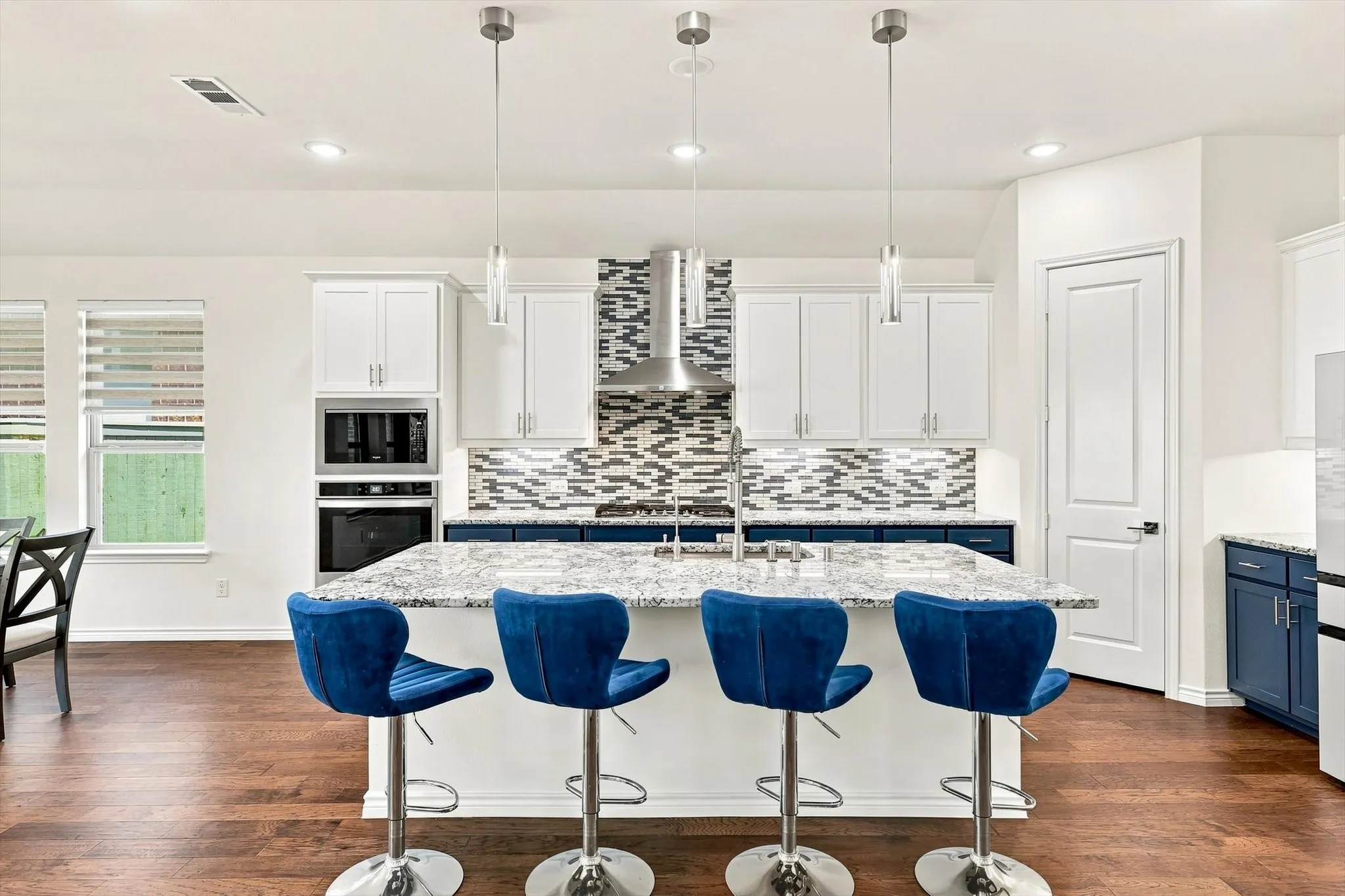 Kitchen featuring a central island with a light-toned countertop, wood-finish flooring, two-toned cabinetry, and stainless steel appliances