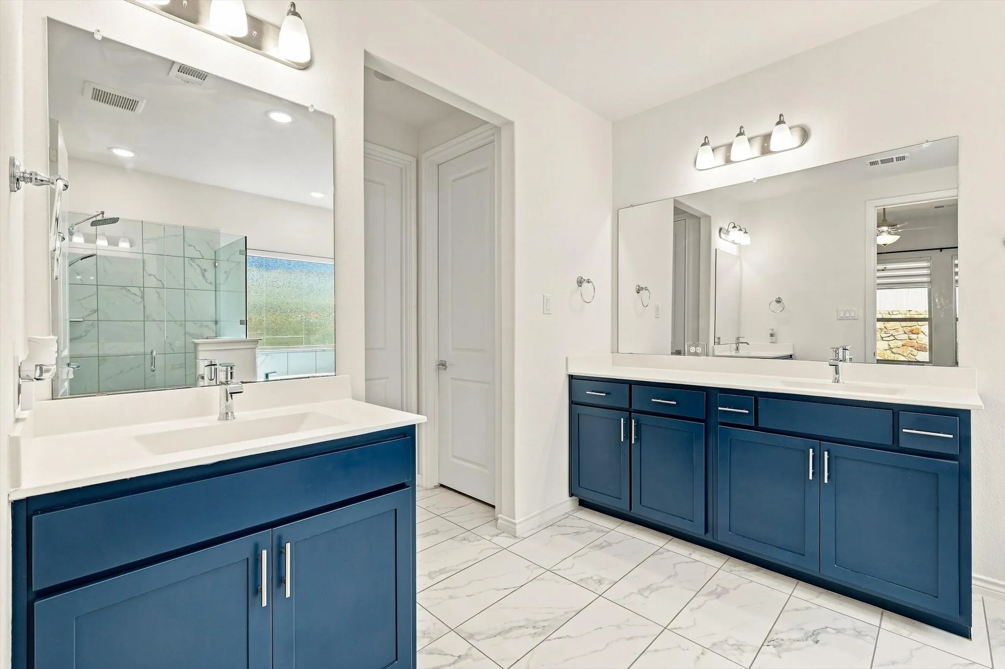 Dual vanities featuring blue cabinetry and white countertops