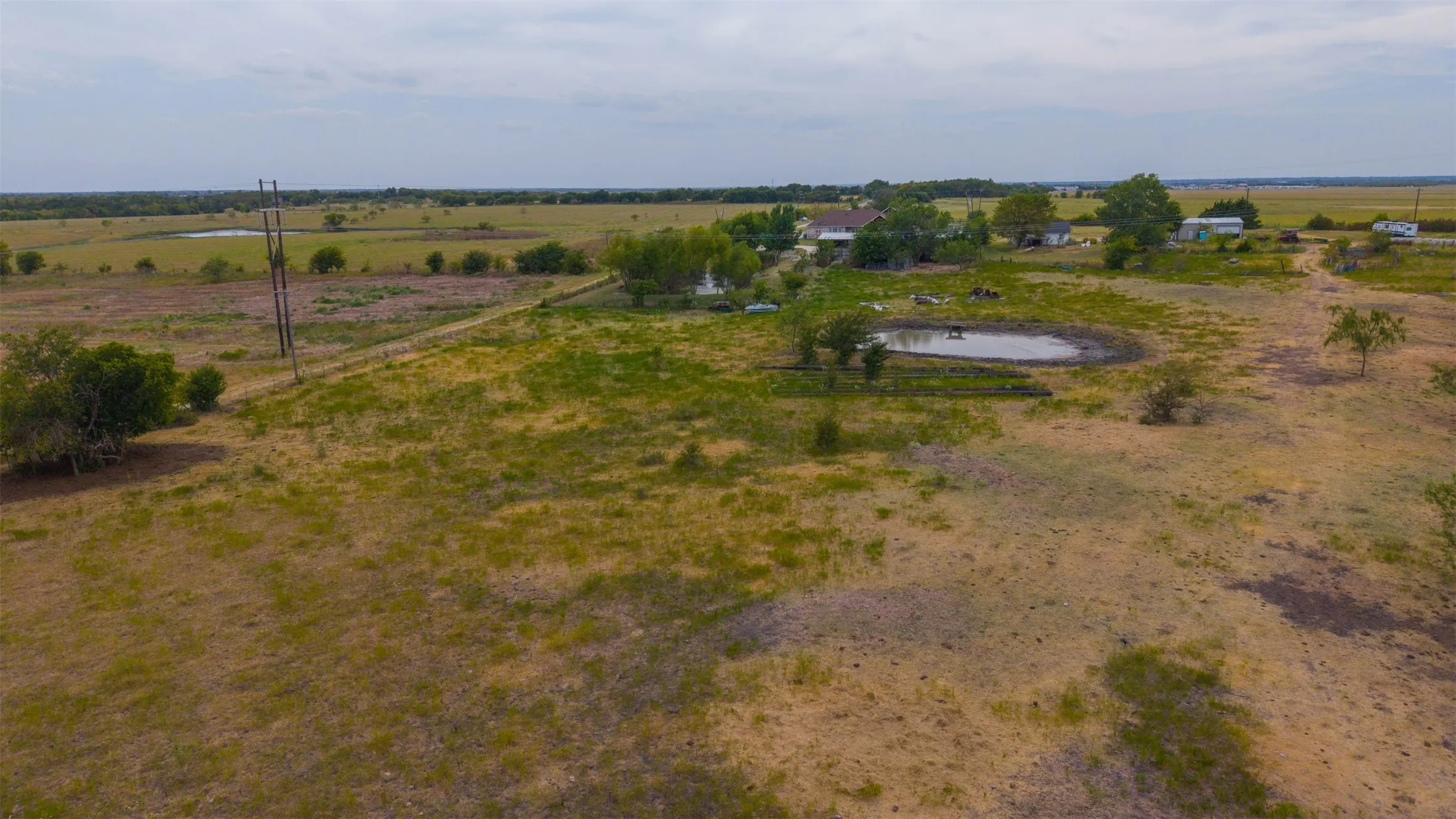 Expansive rural property featuring a primary residence, multiple accessory structures, and a pond