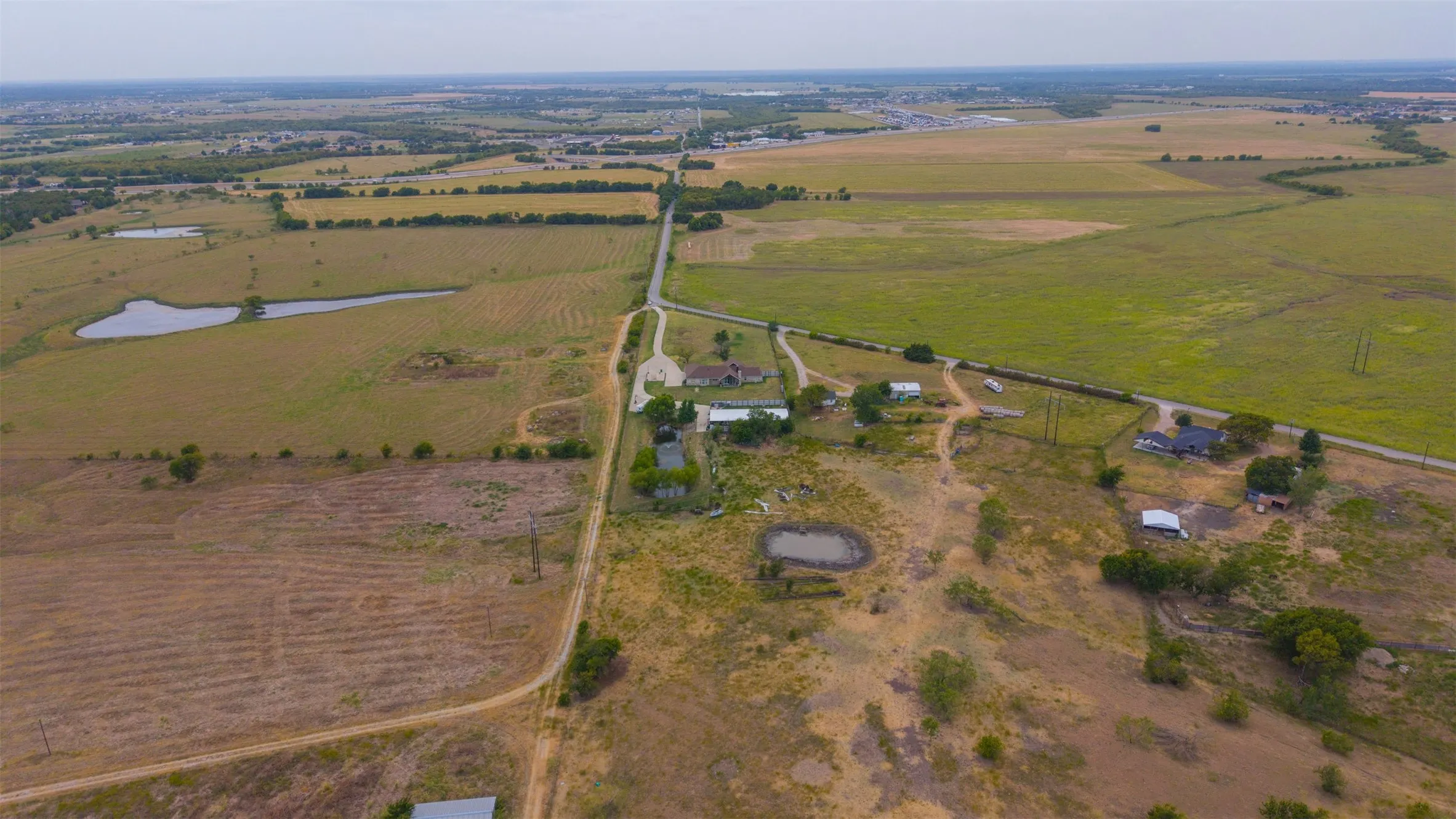 Expansive rural property featuring multiple pastures, a developed pond, and a gravel road access