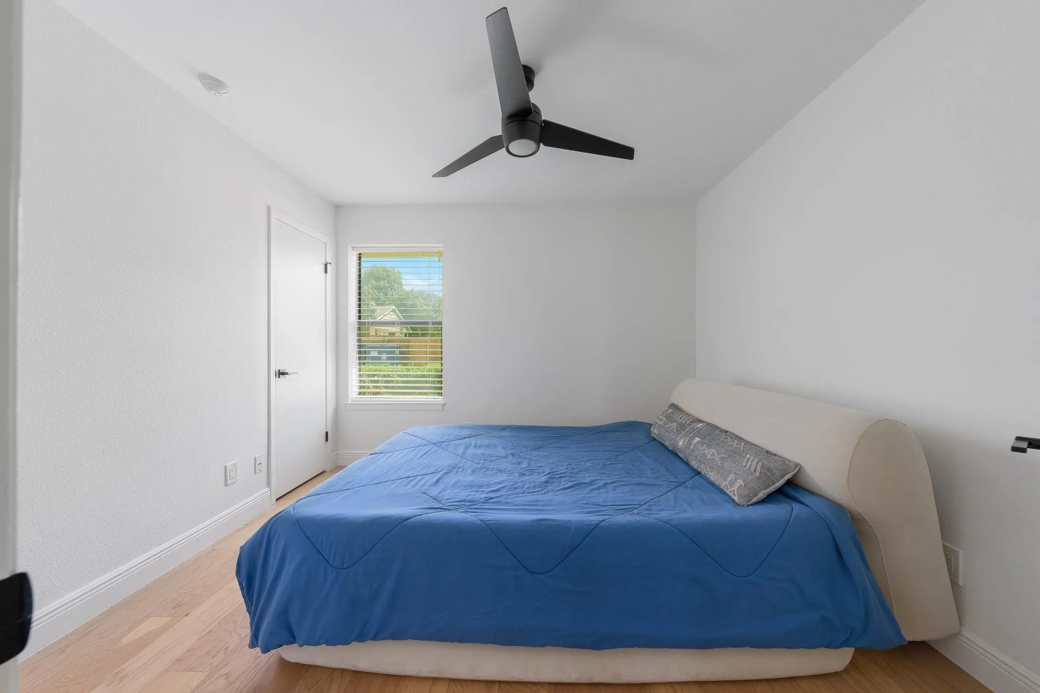Light wood-finish flooring, white walls, and a window with blinds